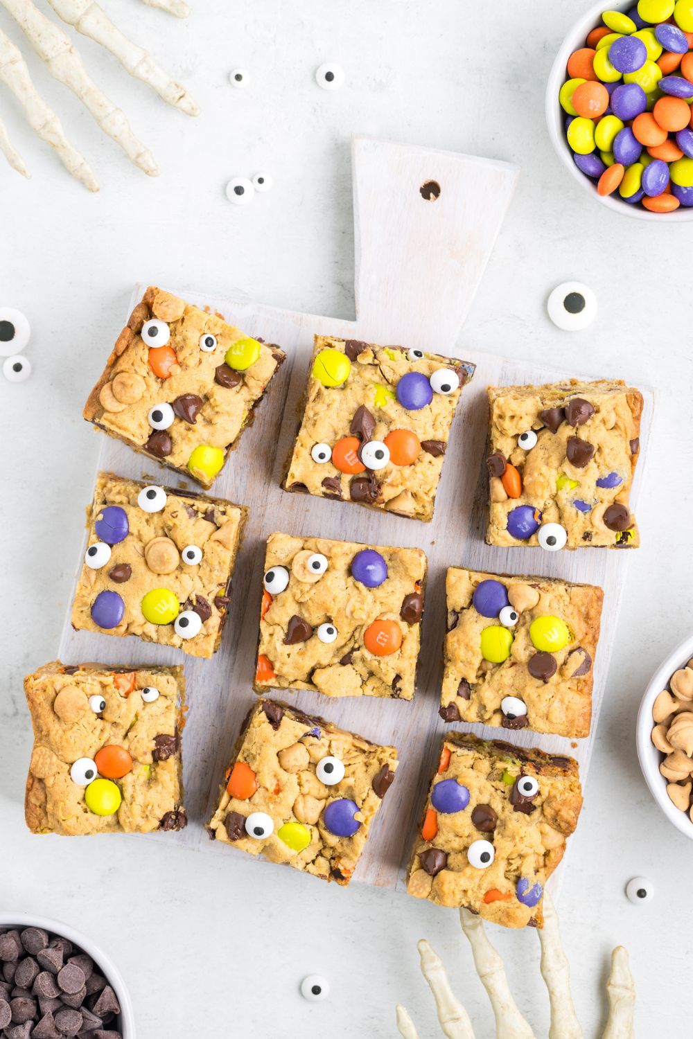 bars scattered on table with Halloween decorations around it and a bowl of M&Ms