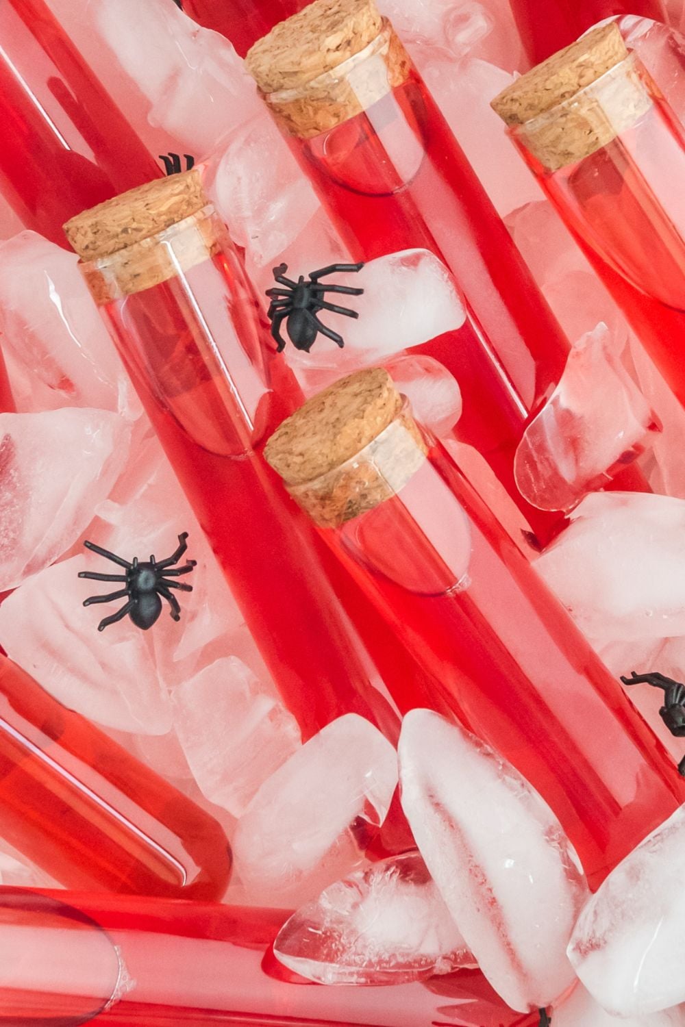 close up of red test tubes in container with ice cubes and fake spiders