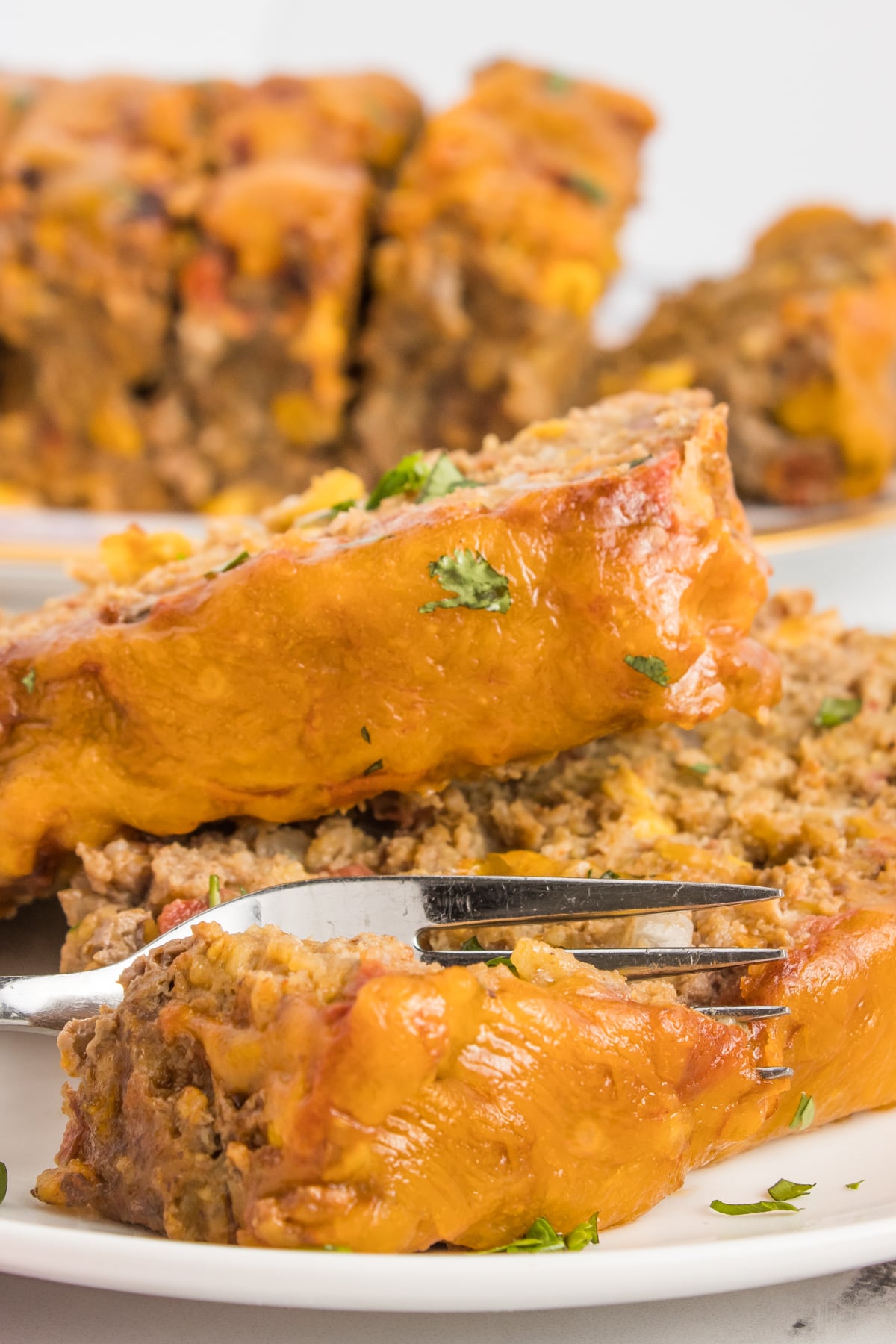 Taco Meatloaf sliced with a fork cutting into it