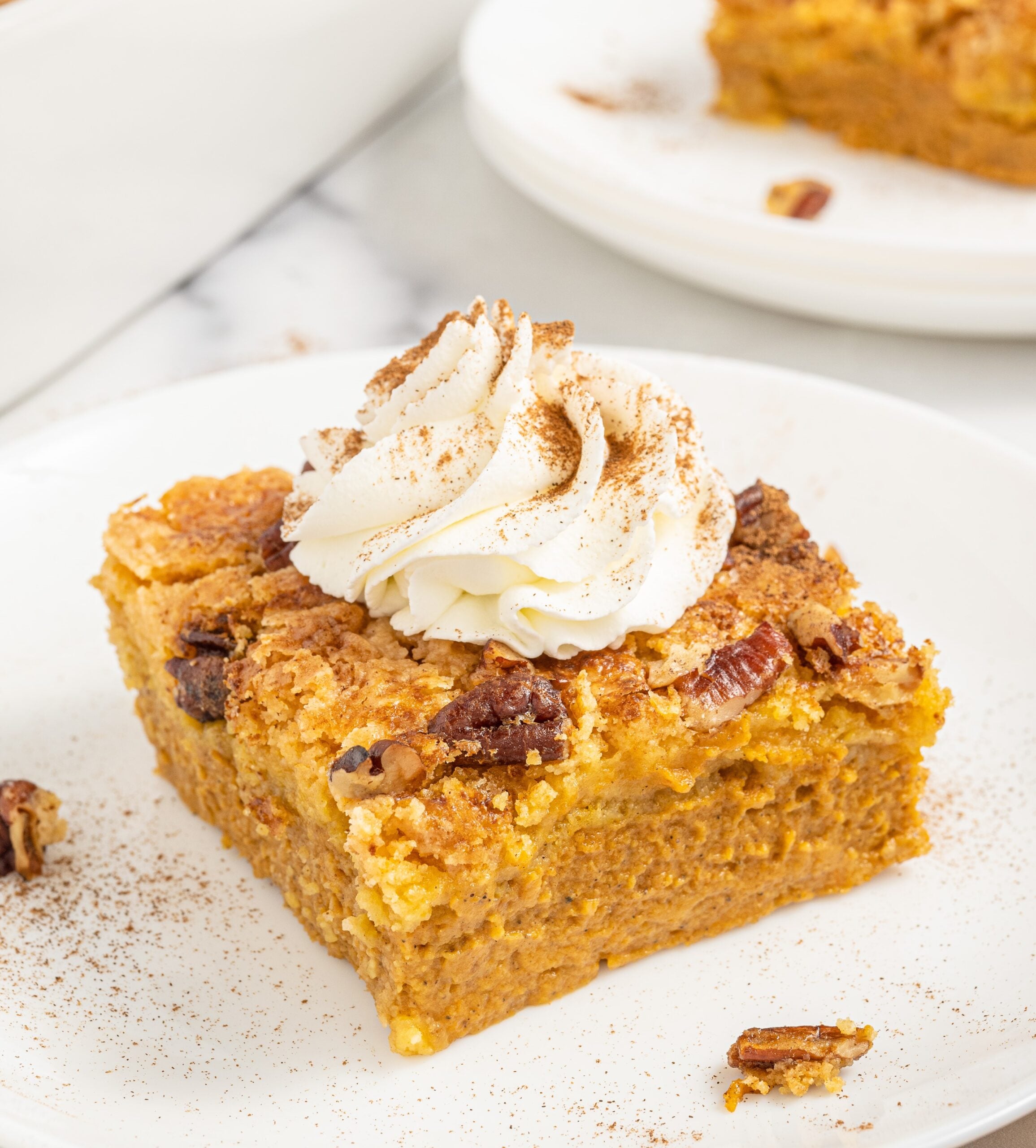 Pumpkin Dump Cake on a white plate with a dollop of whipped cream on top