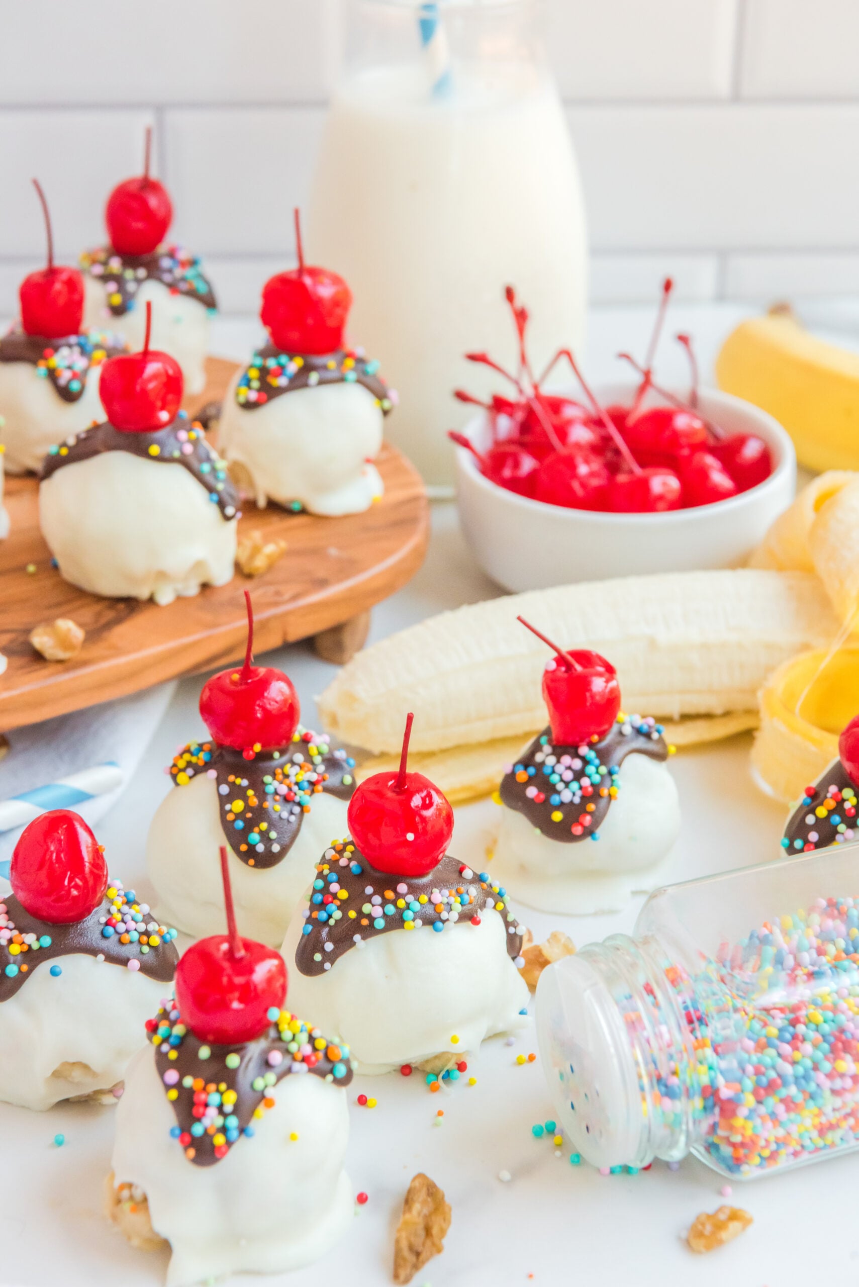 Front view of Banana Truffles surrounded by bananas, a bowl of cherries and nuts.