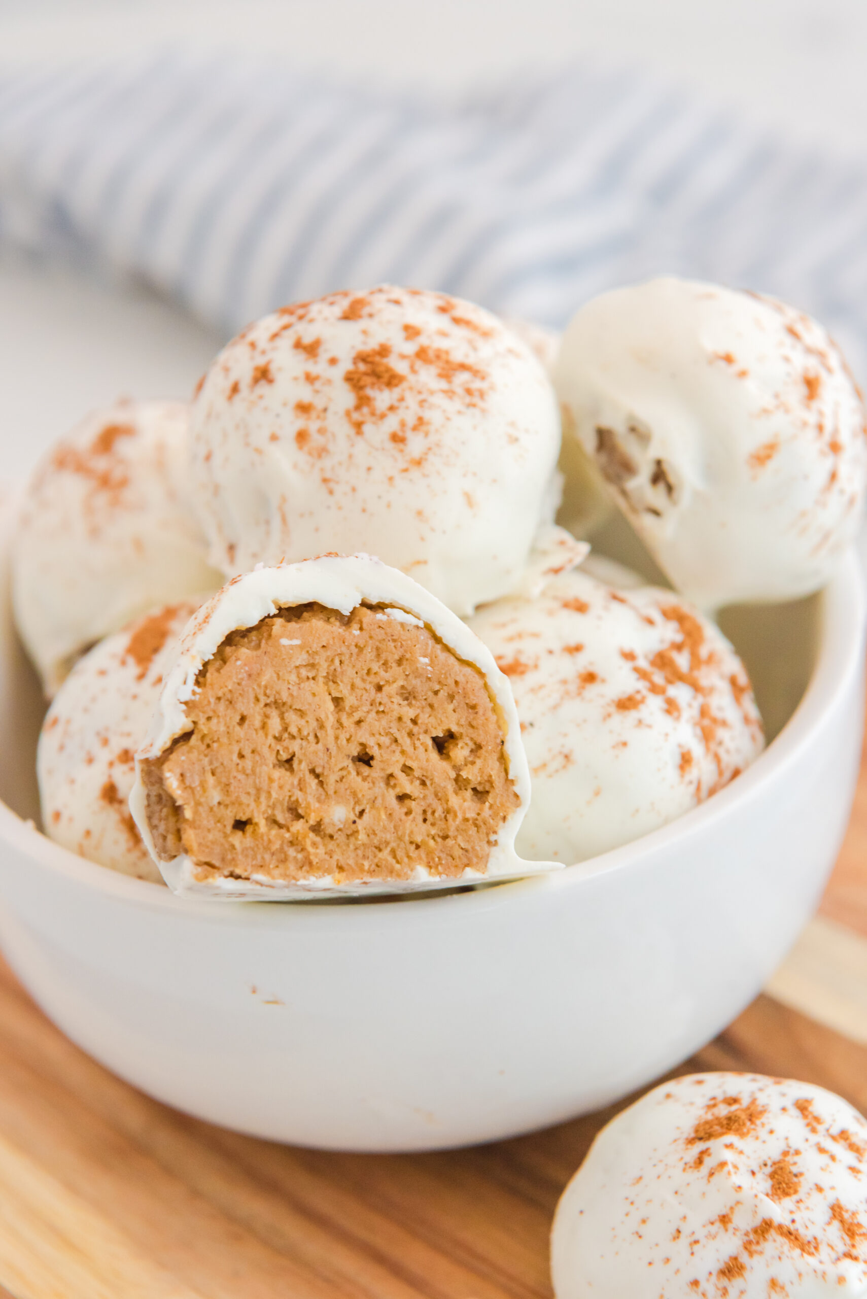 no bake pumpkin balls in a white bowl with one cut open to show texture 