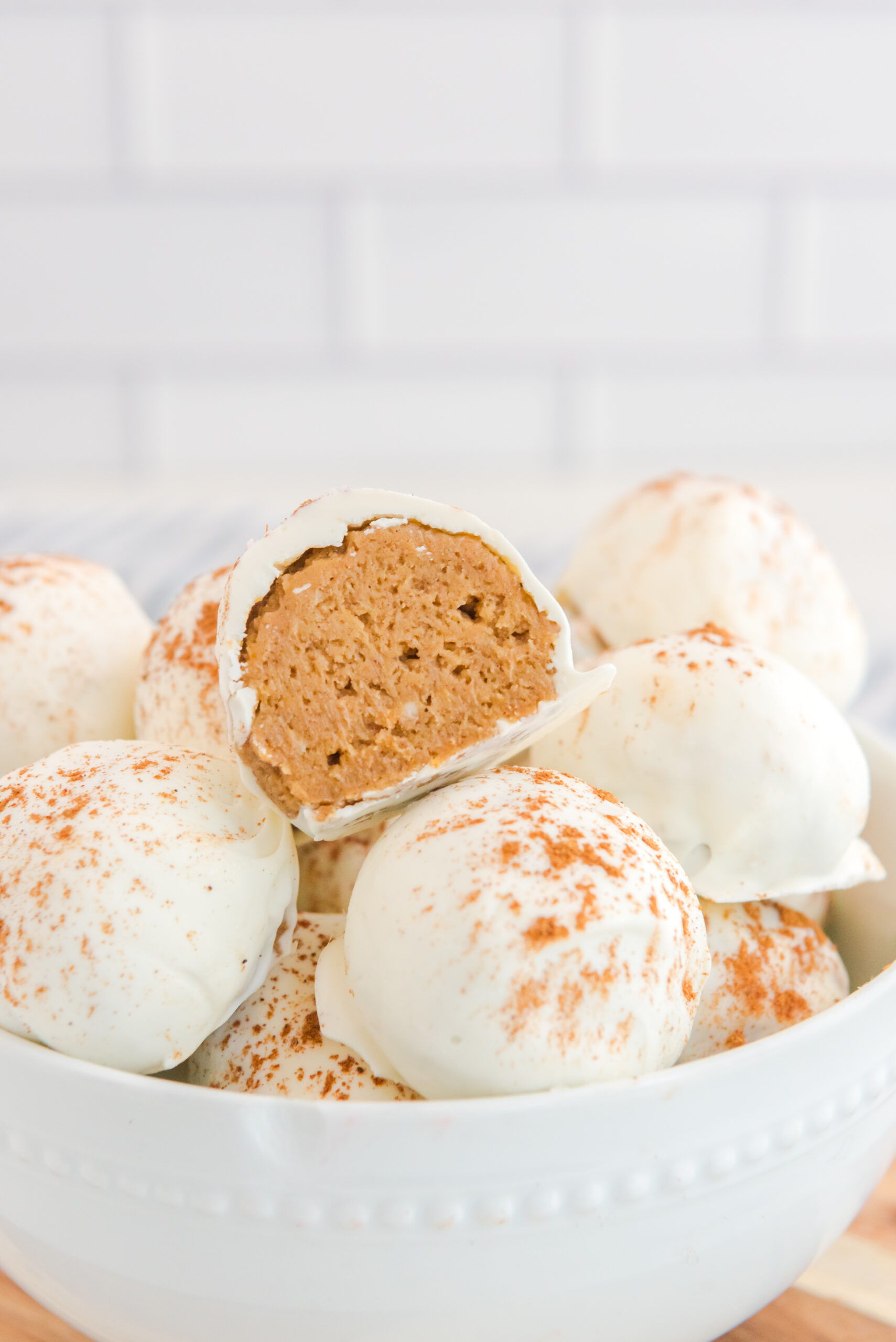 no bake pumpkin balls in a white bowl with one cut open to show inside