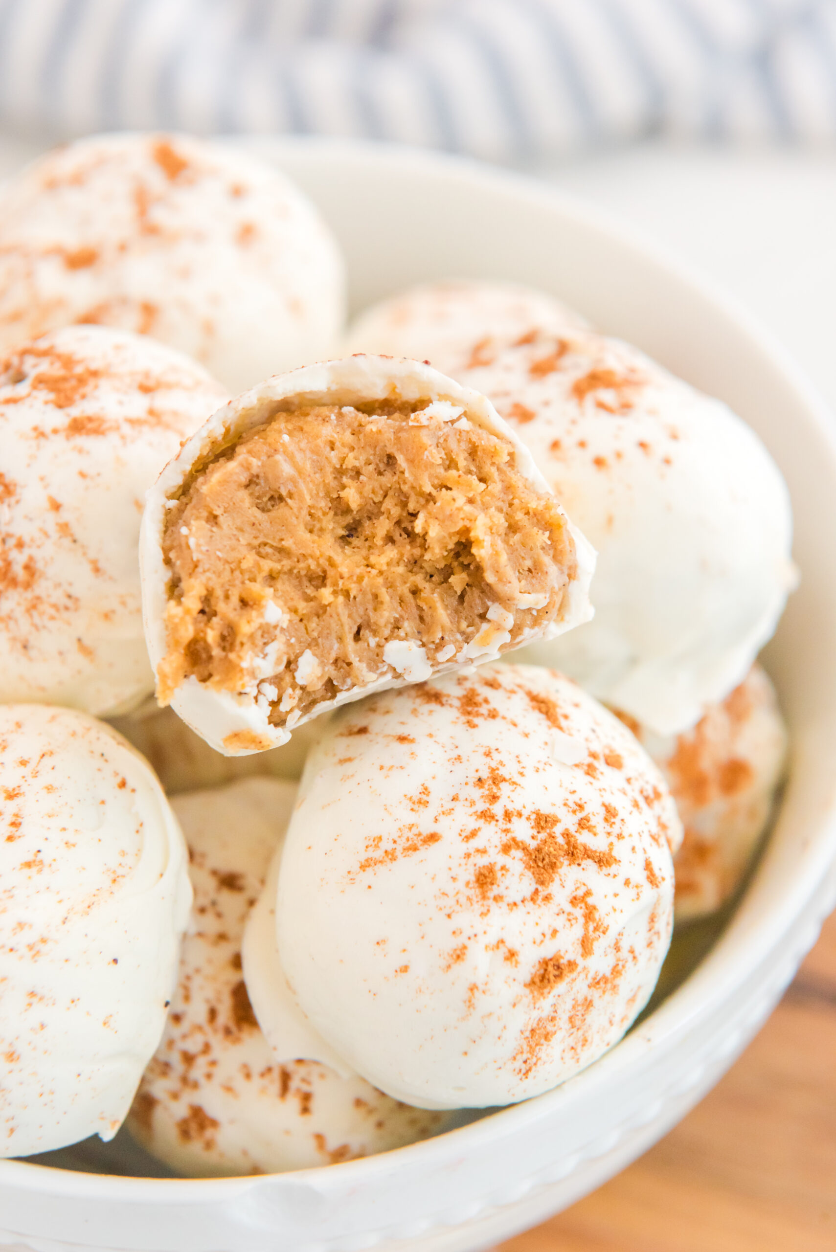 no bake pumpkin balls with a bite taken out of one that is stacked in bowl
