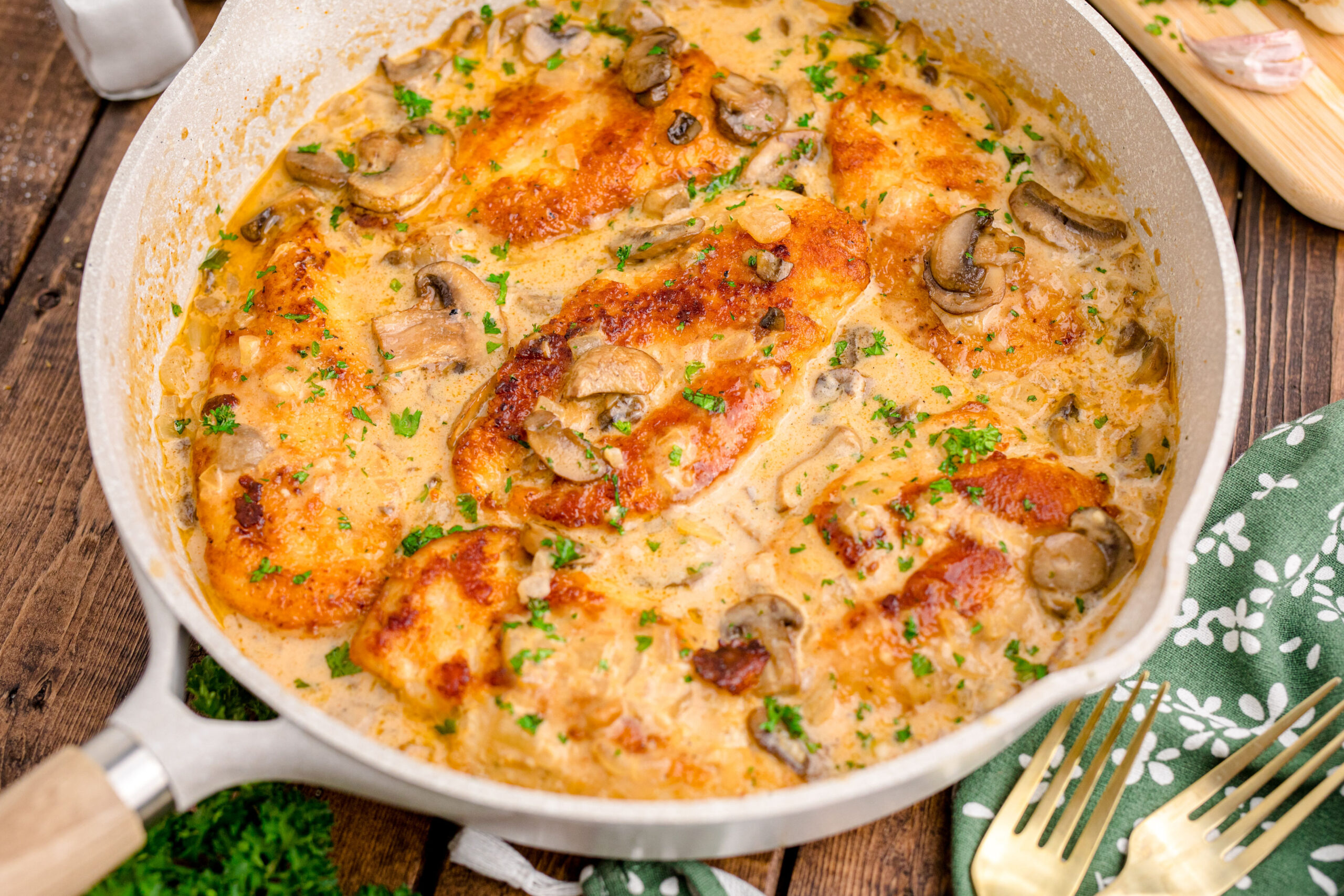 Chicken Marsala in a white skillet on a dark wood table 
