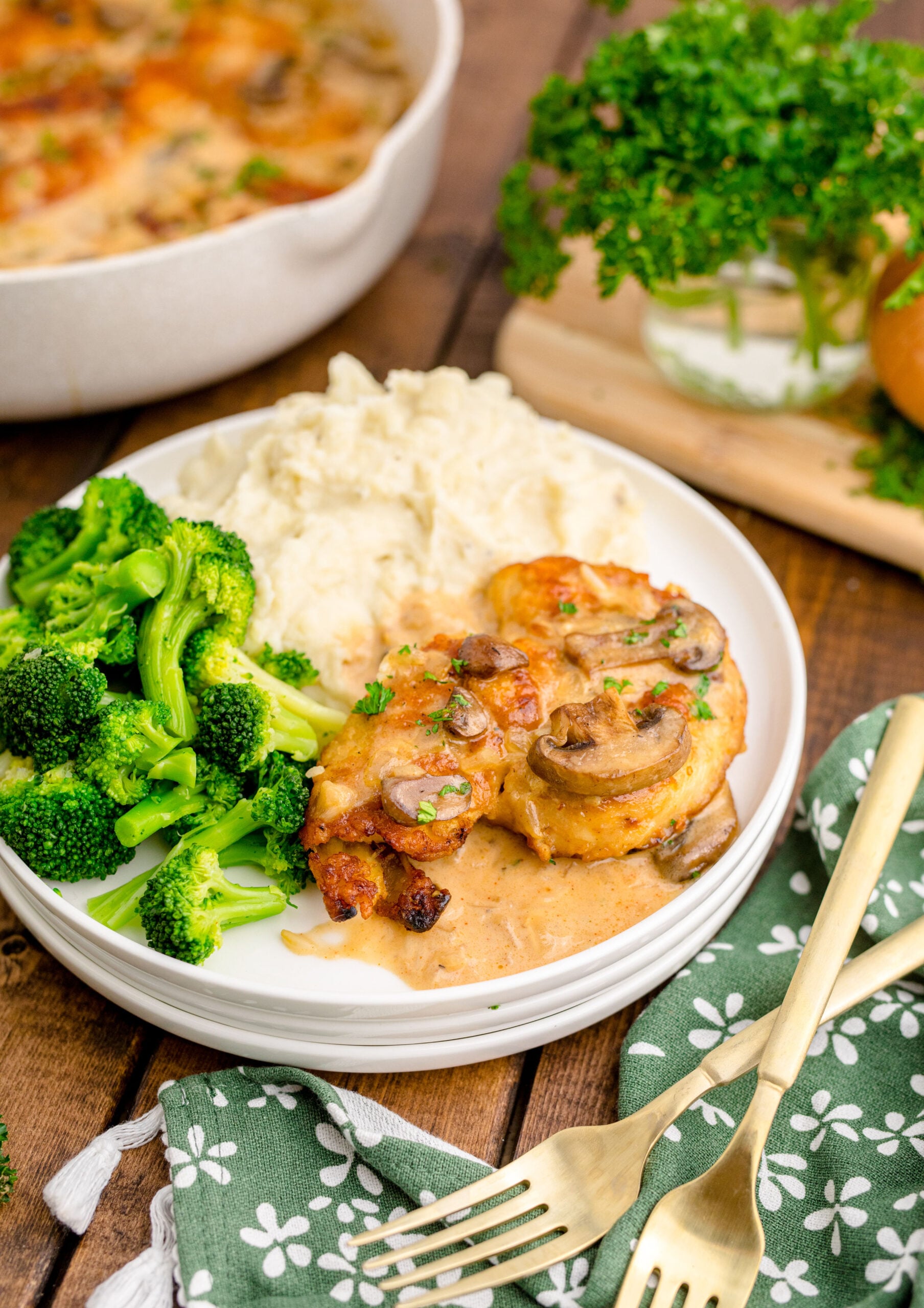 Chicken Marsala on a white plate with a side of broccoli and mashed potatoes 