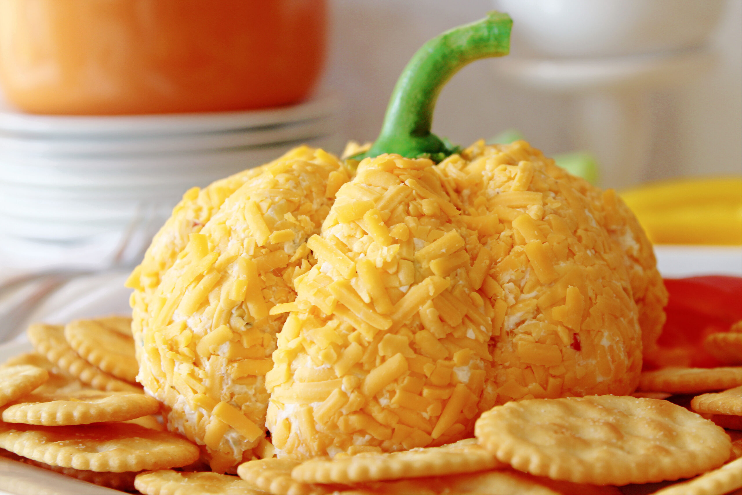 pumpkin cheeseball on a white plate with sliced peppers and crackers