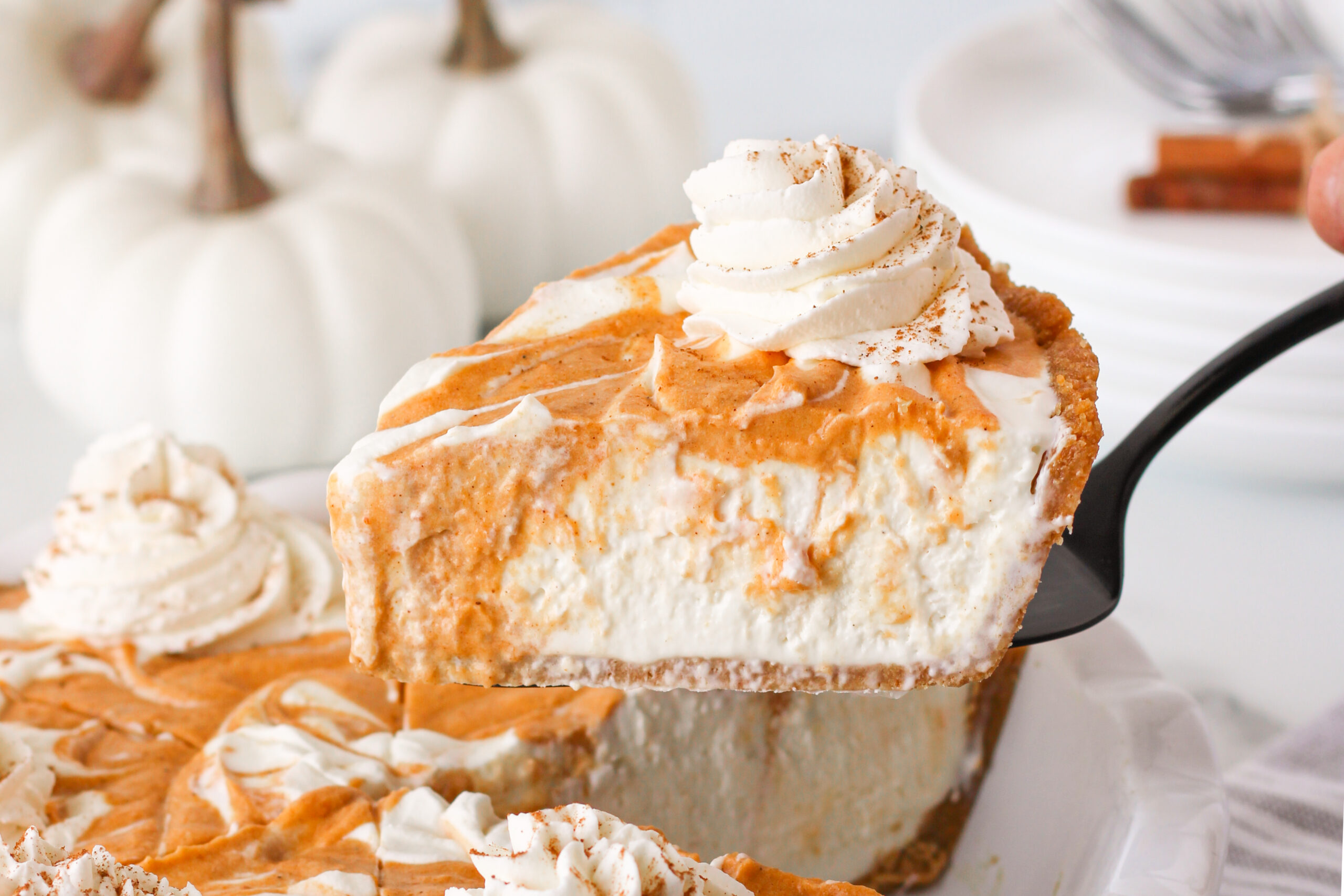 Pumpkin Ice Cream Pie in a white baking dish with a slice being lifted up on a serving spoon