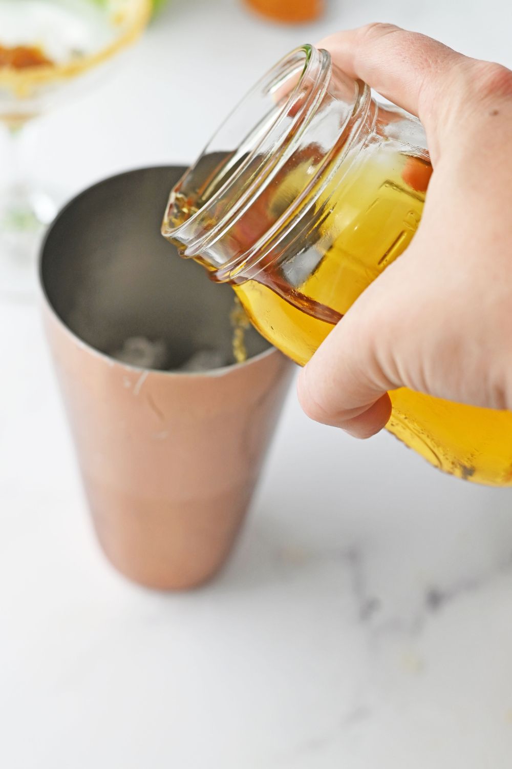 pouring apple juice into a cocktail shaker