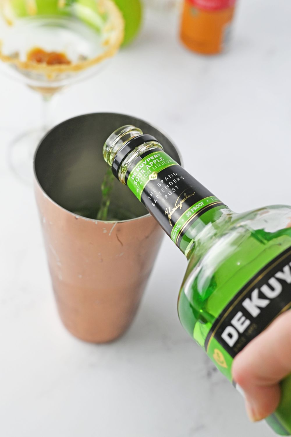 pouring sour pucker into a cocktail shaker 
