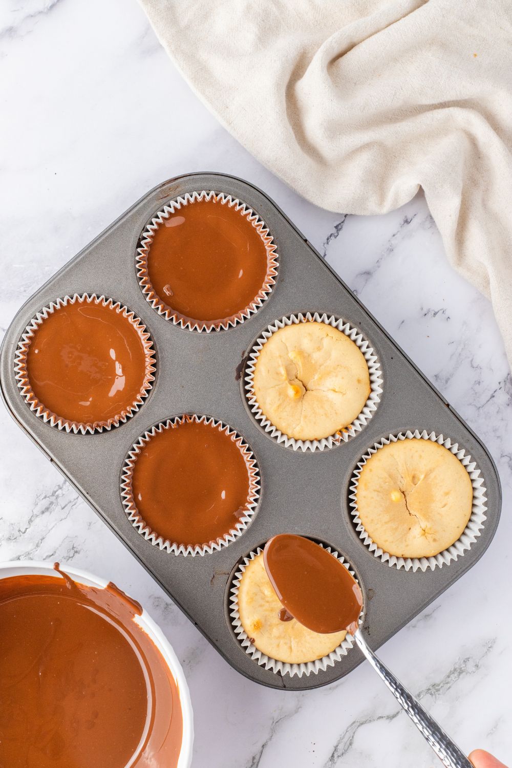 spooning chocolate on top of peanut butter cheesecakes 
