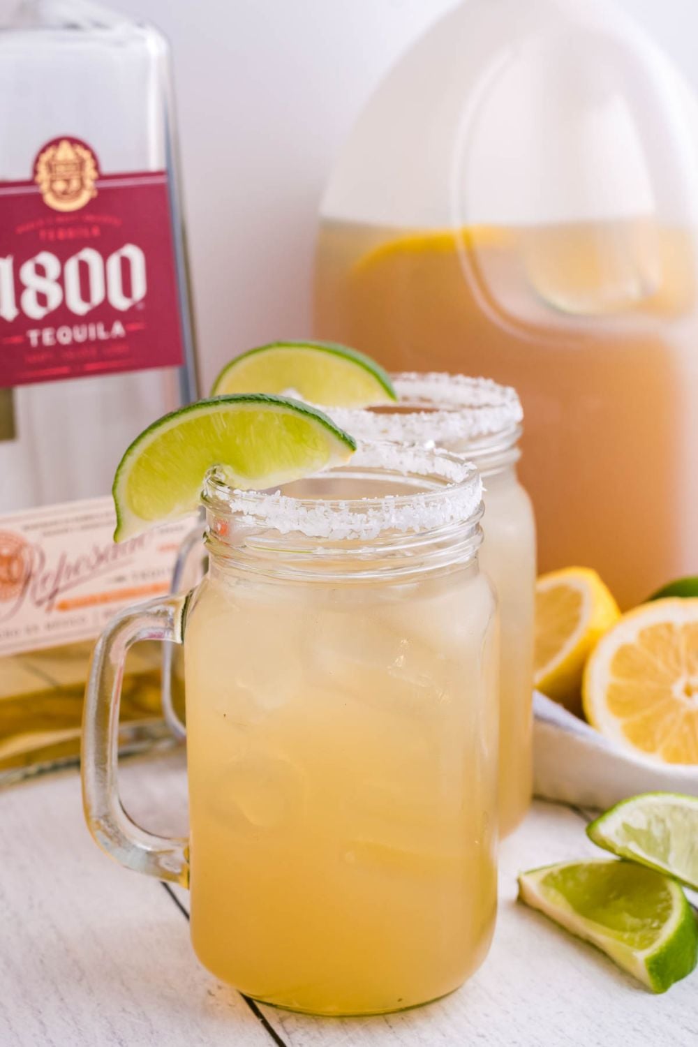 Gallon Margarita in mason jars that are garnished with salt and wedges