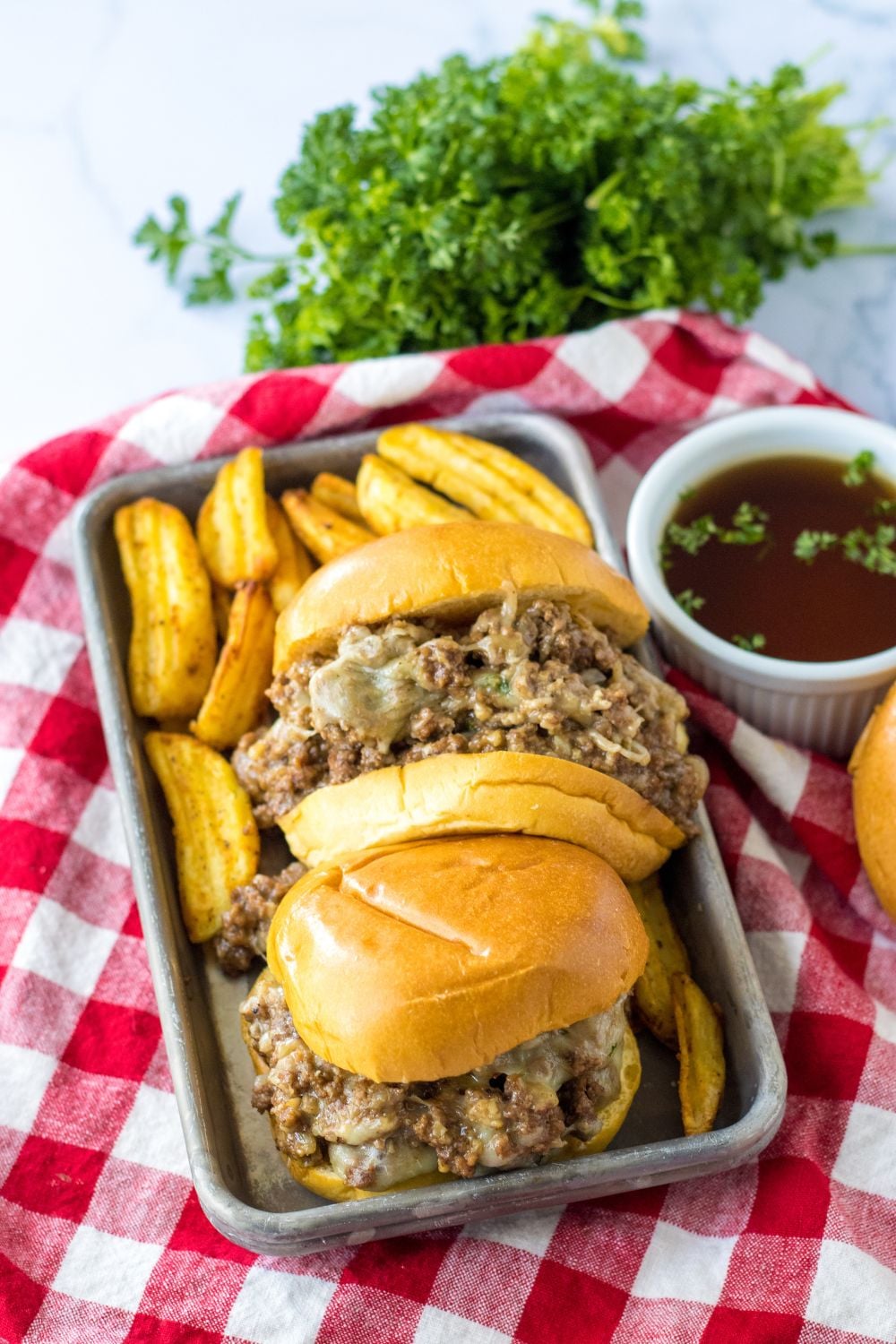 beef au jus sandwiches on a tray with red plaid napkin under it
