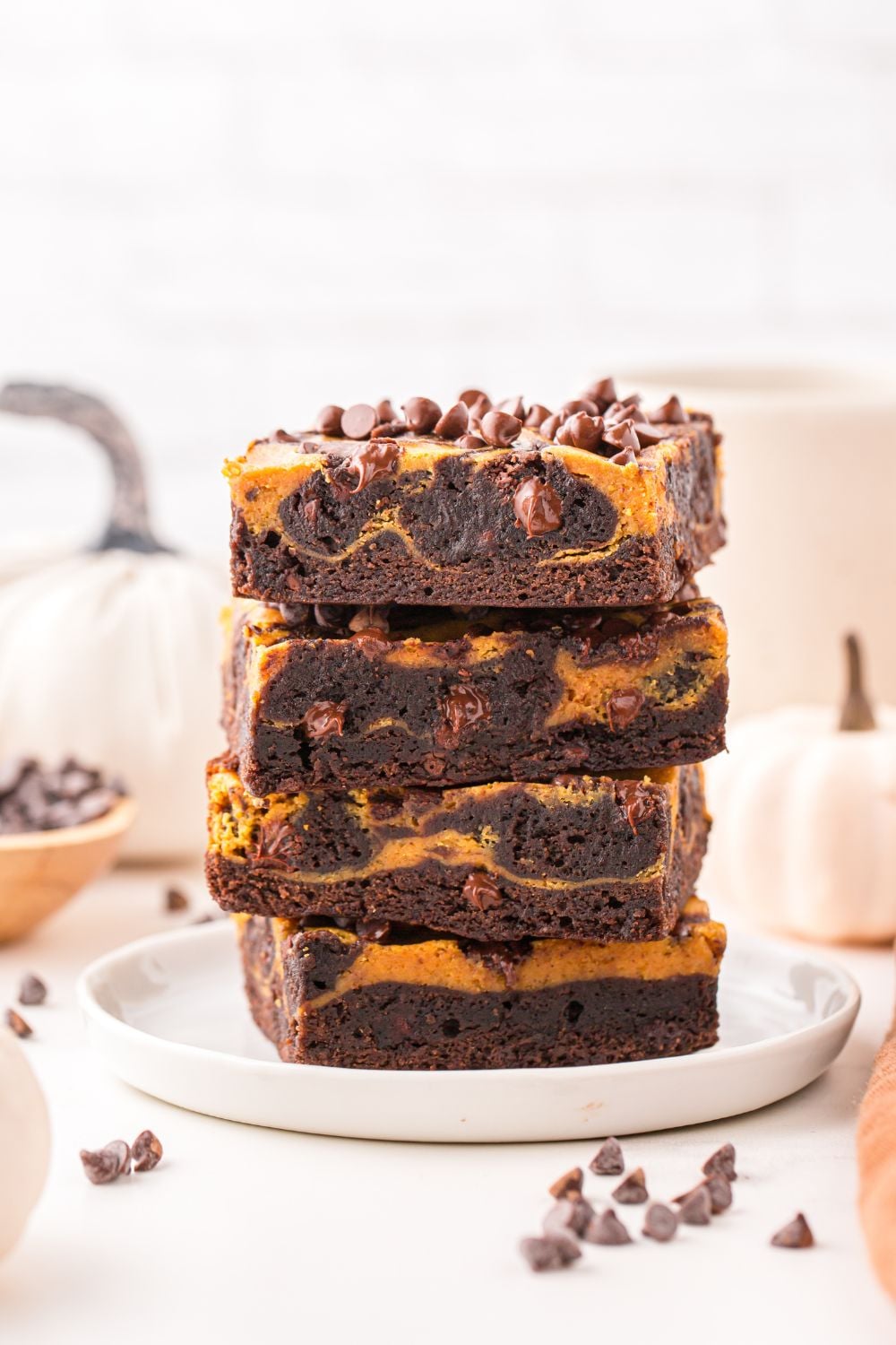 brownies stacked on top of each other on plate with chocolate chips on table