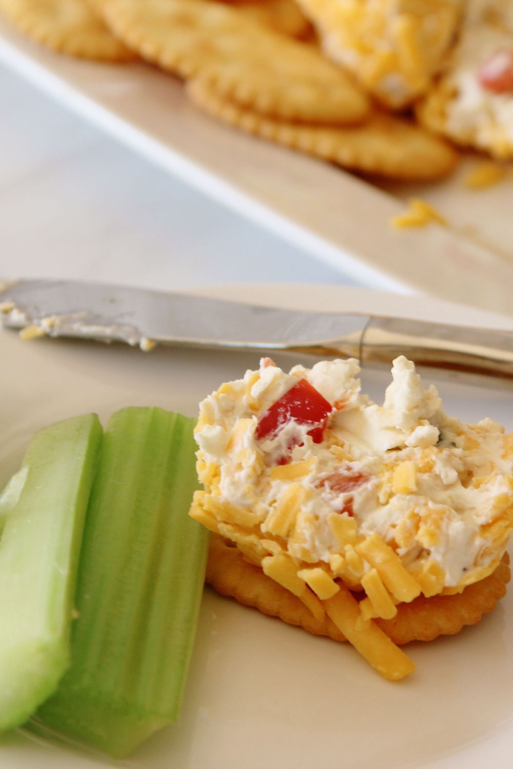 cracker with cheeseball and celery sticks on plate