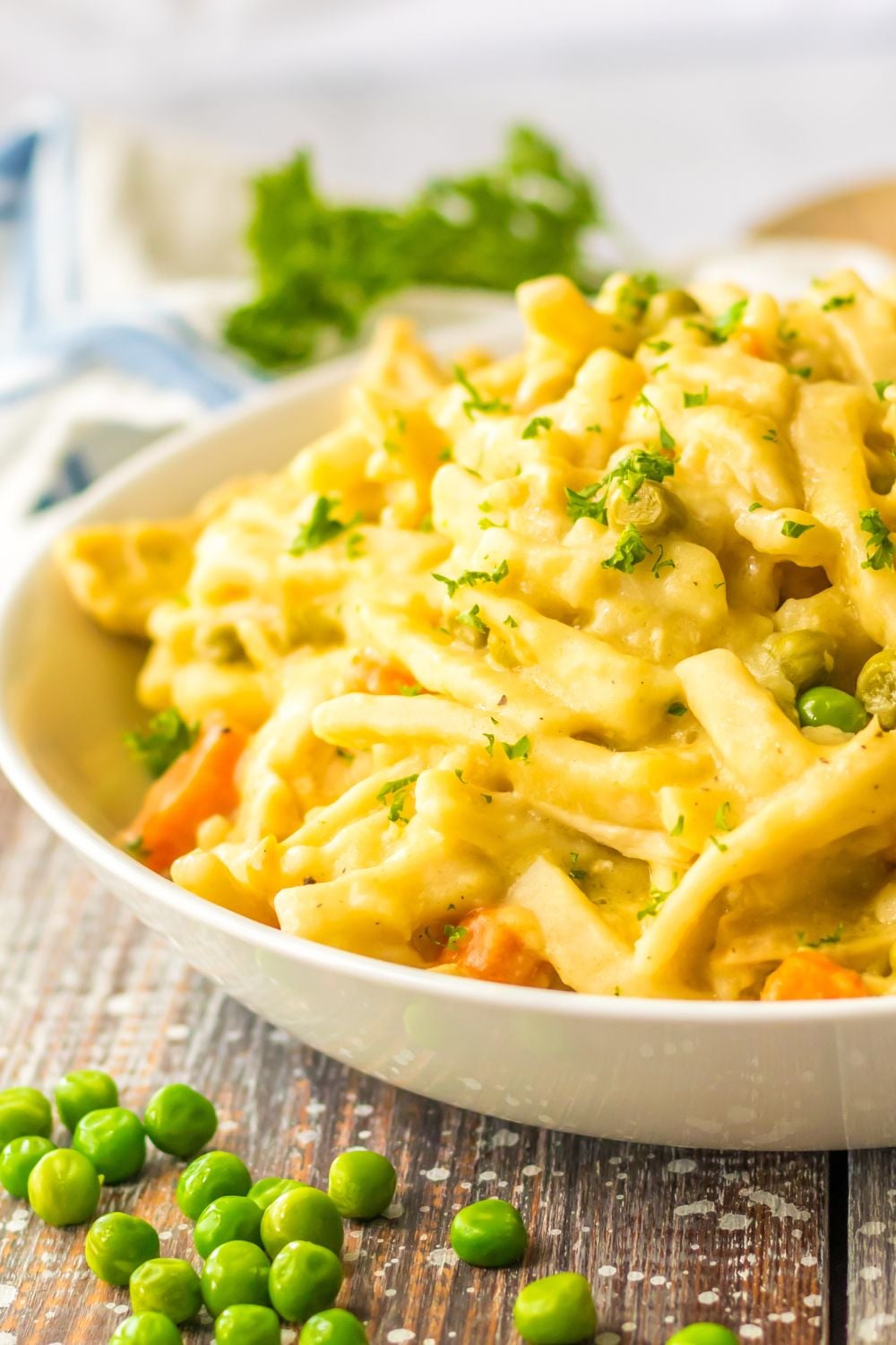 white bowl with chicken and noodles and peas spread out on table