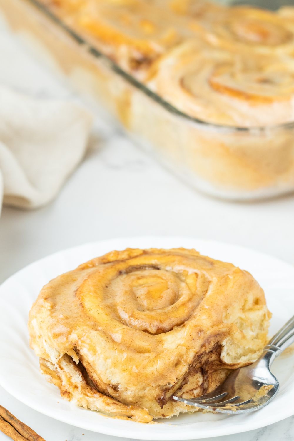 cinnamon roll on plate with casserole with more rolls