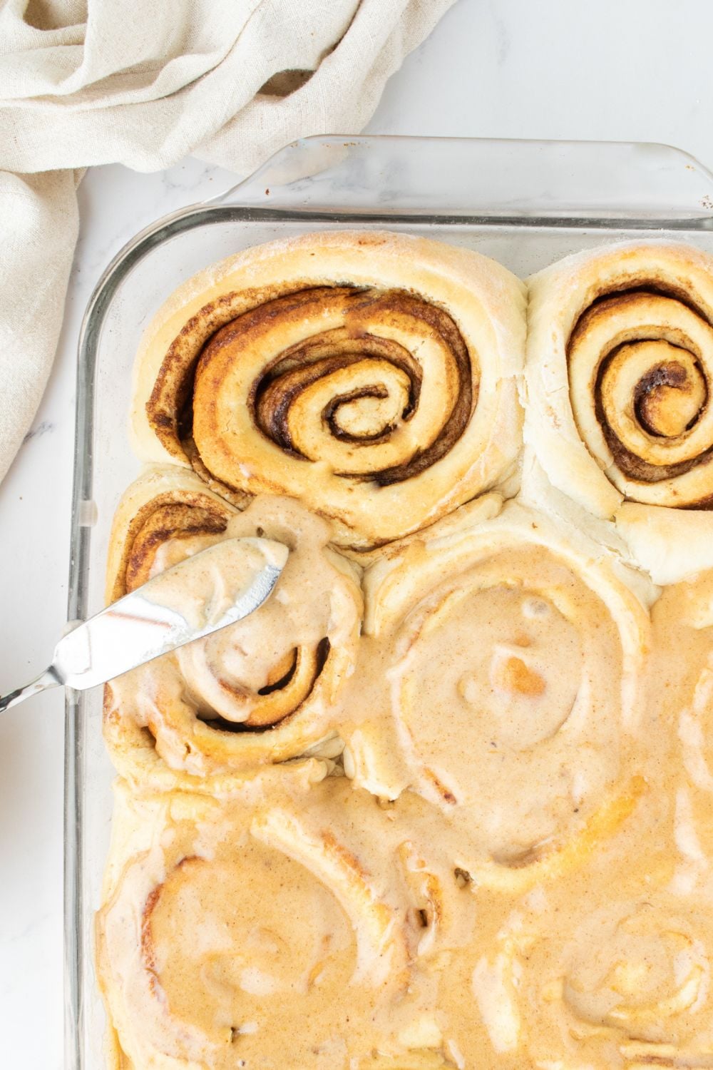 spreading frosting on cinnamon rolls