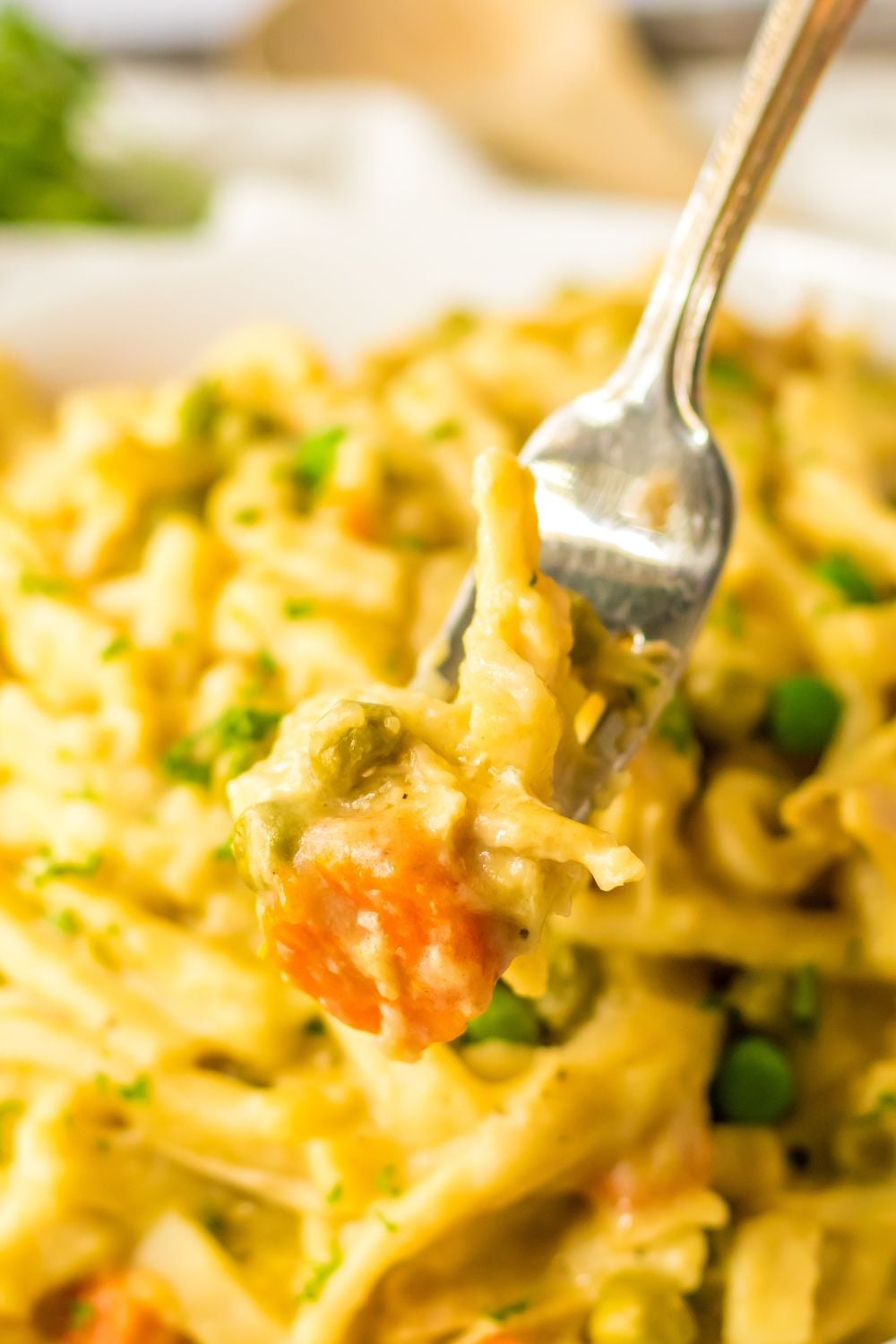 fork with chicken and noodles on it above a bowl