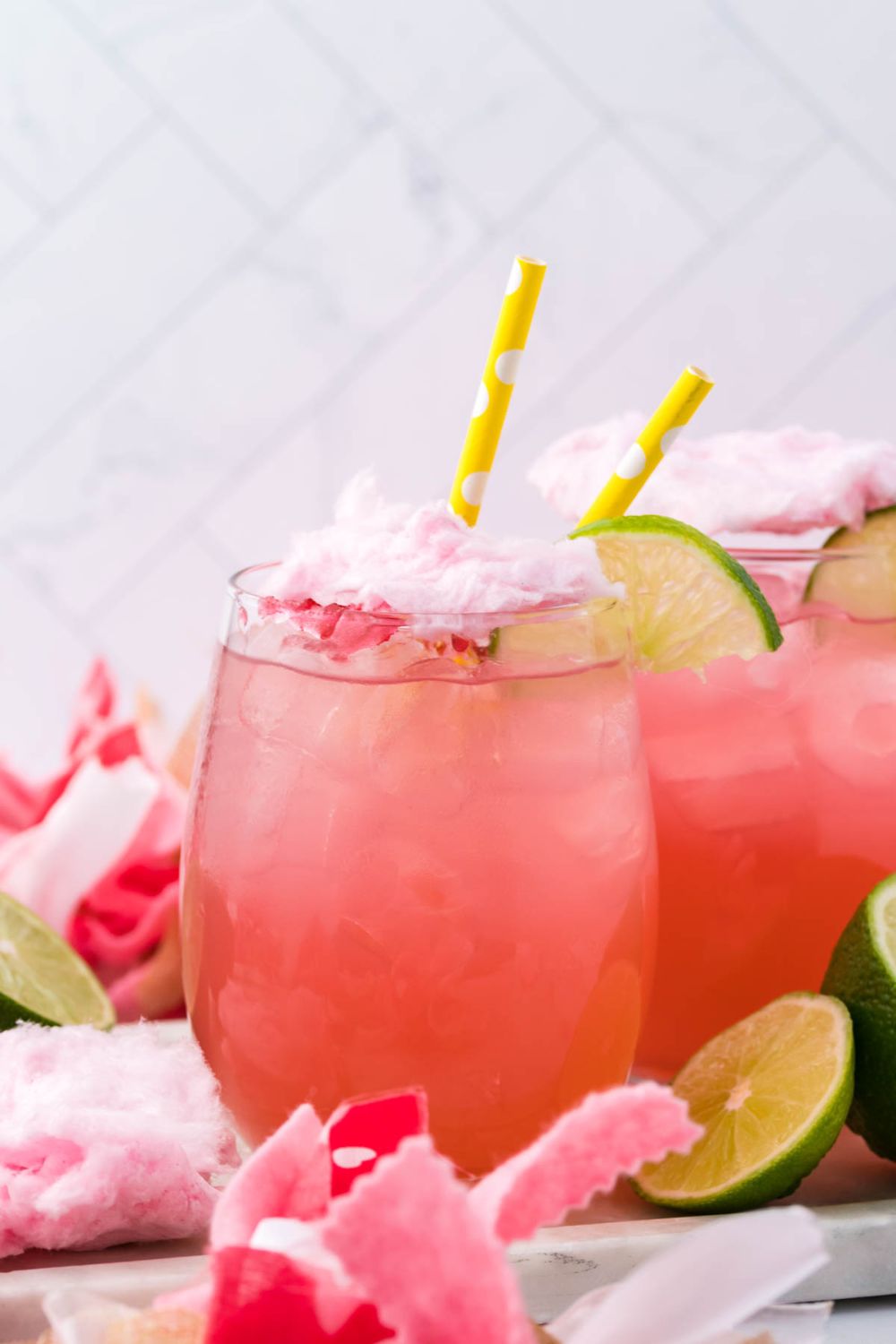 drink with cotton candy on top on table with limes around it