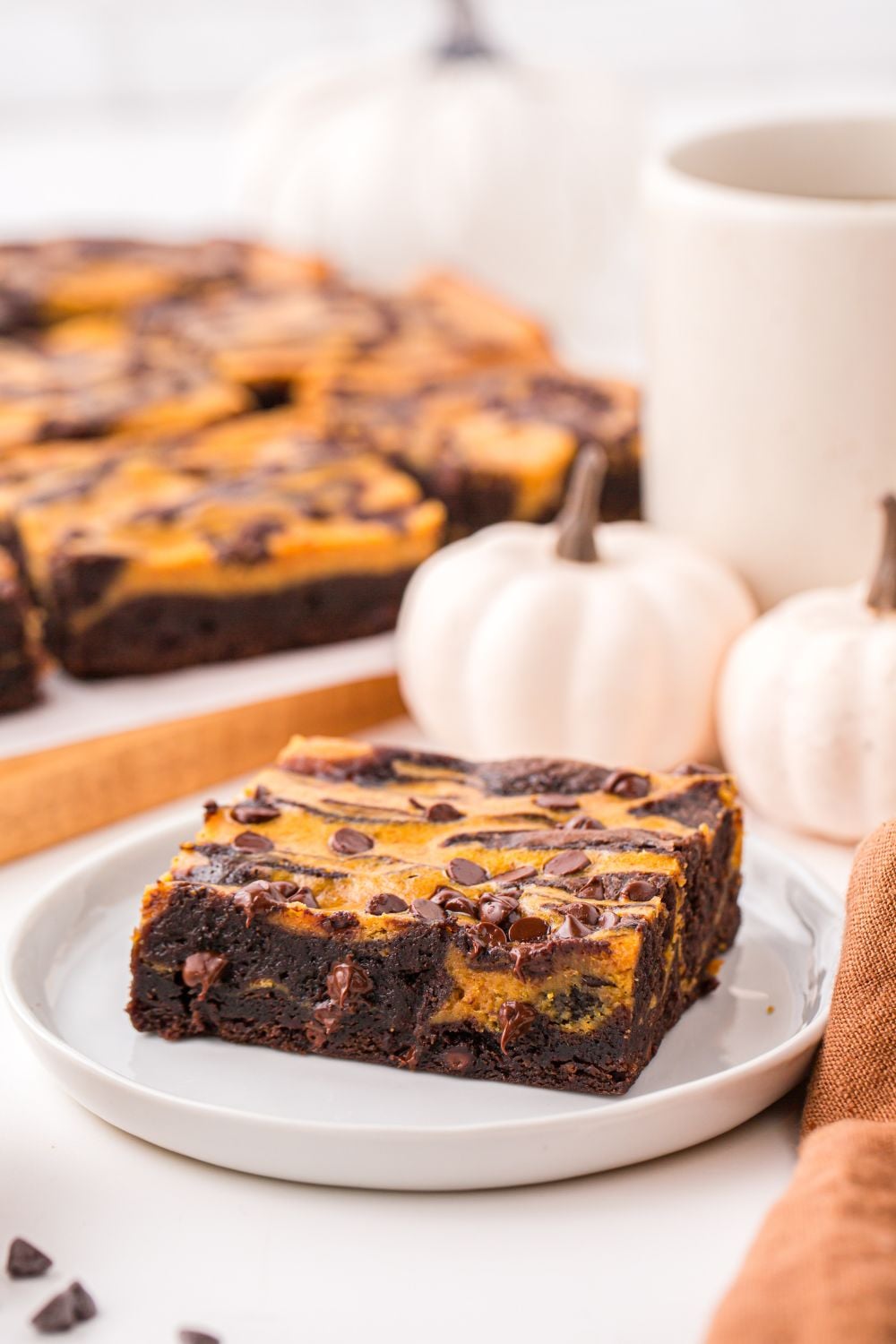 sliced brownie on plate with pumpkins behind it