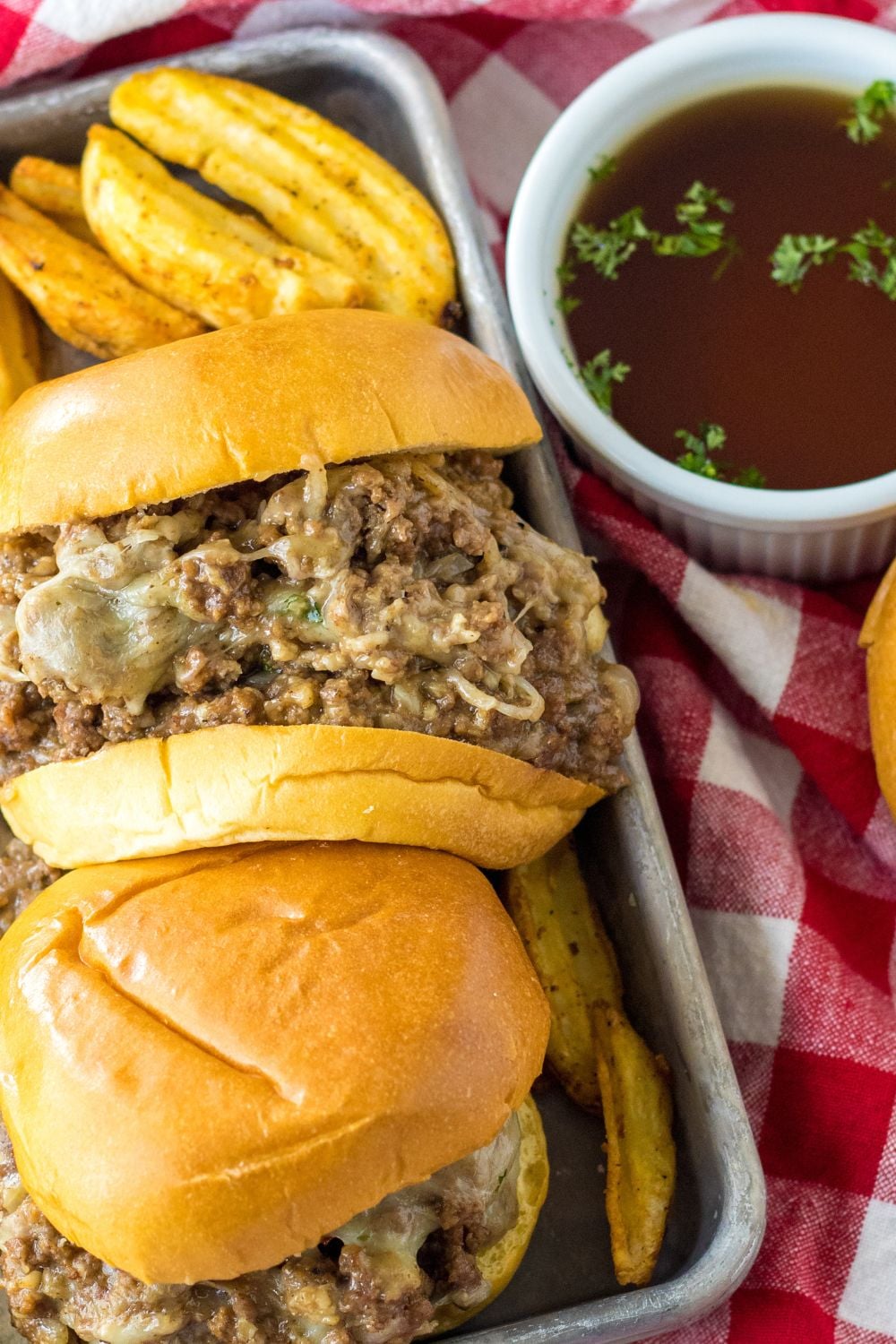 french dip sauce in bowl and sandwiches on side