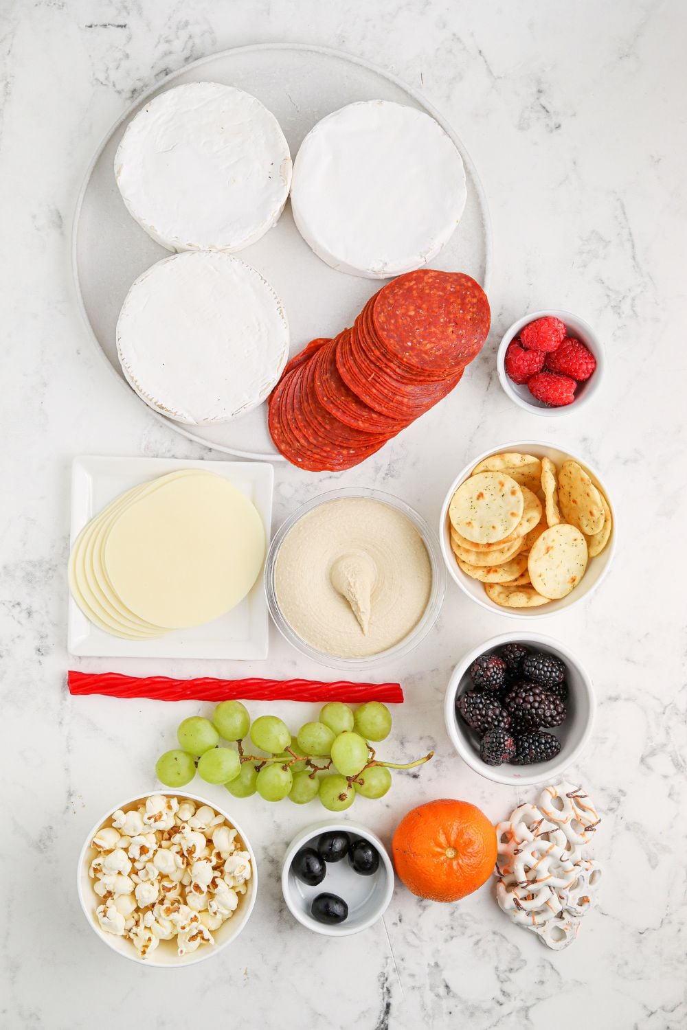 brie, and other ingredients to assemble charcuterie board on table