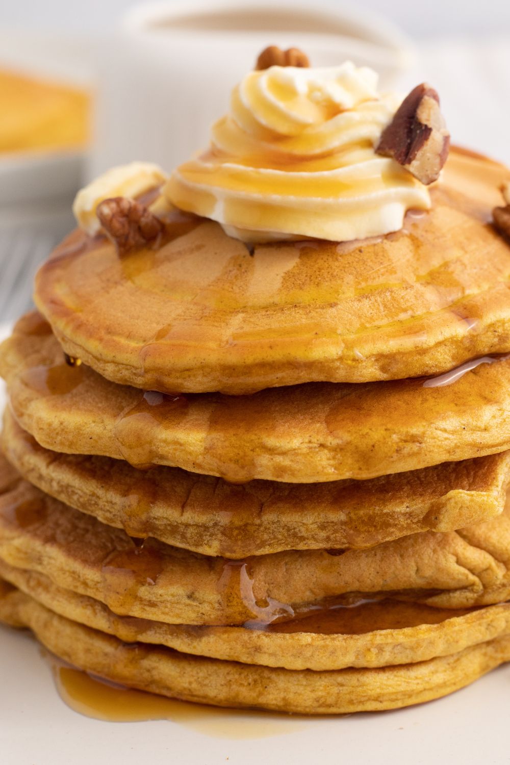 stack of pancakes on plate with whipped cream and nuts on top