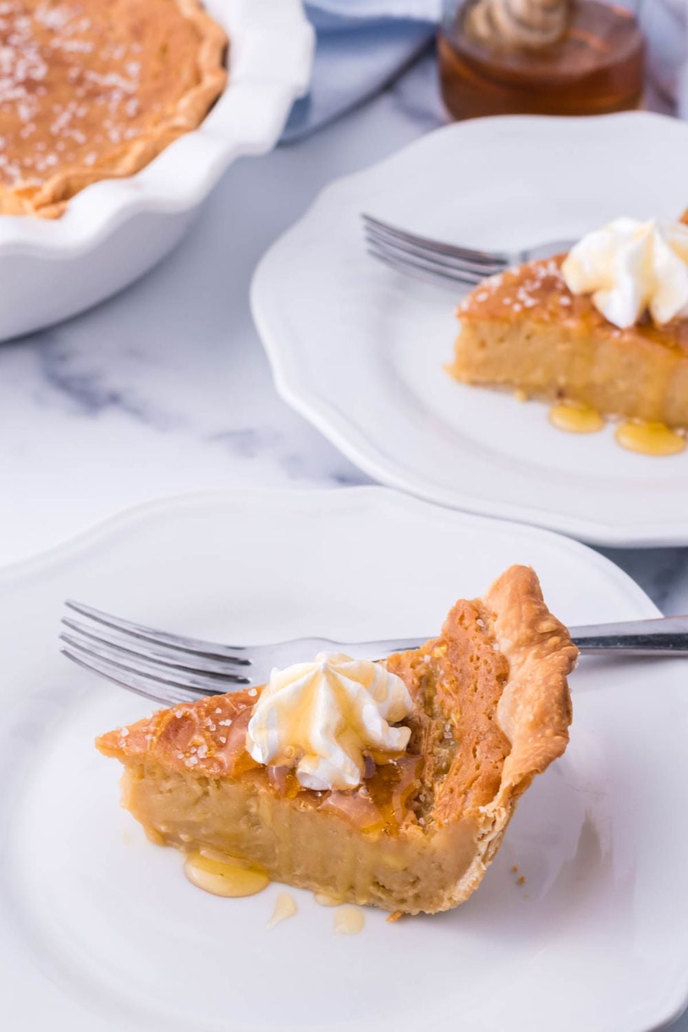 slice of pie on a plate with a fork on it, and another pie plate behind it