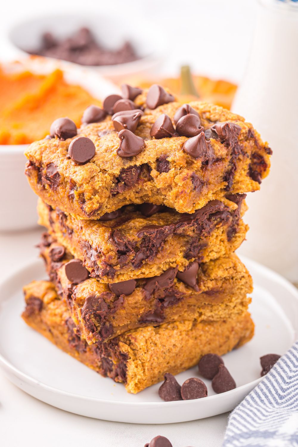 gooey cookie bars stacked on a plate with chocolate chips around it