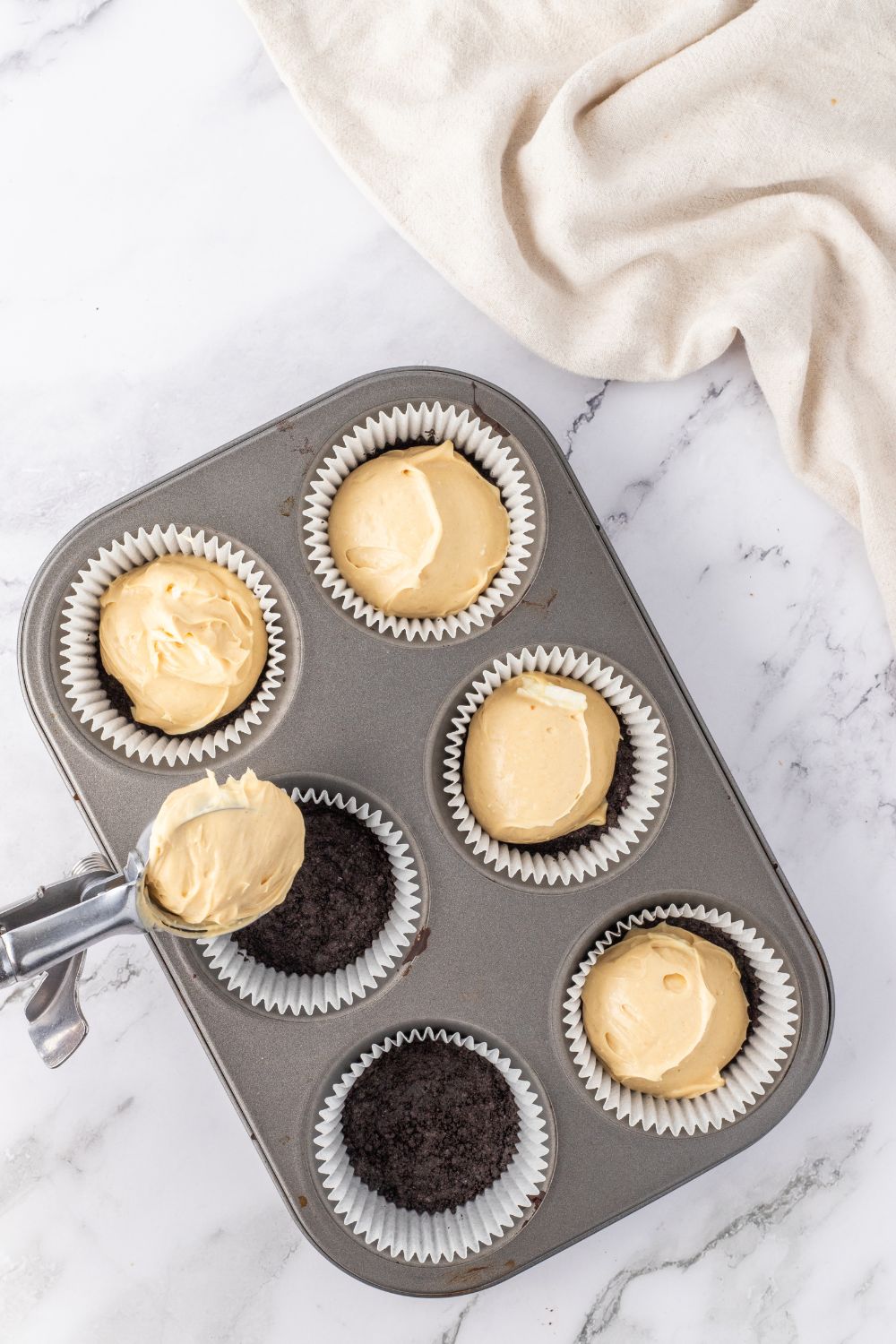 spooning peanut butter cheesecake in pan 