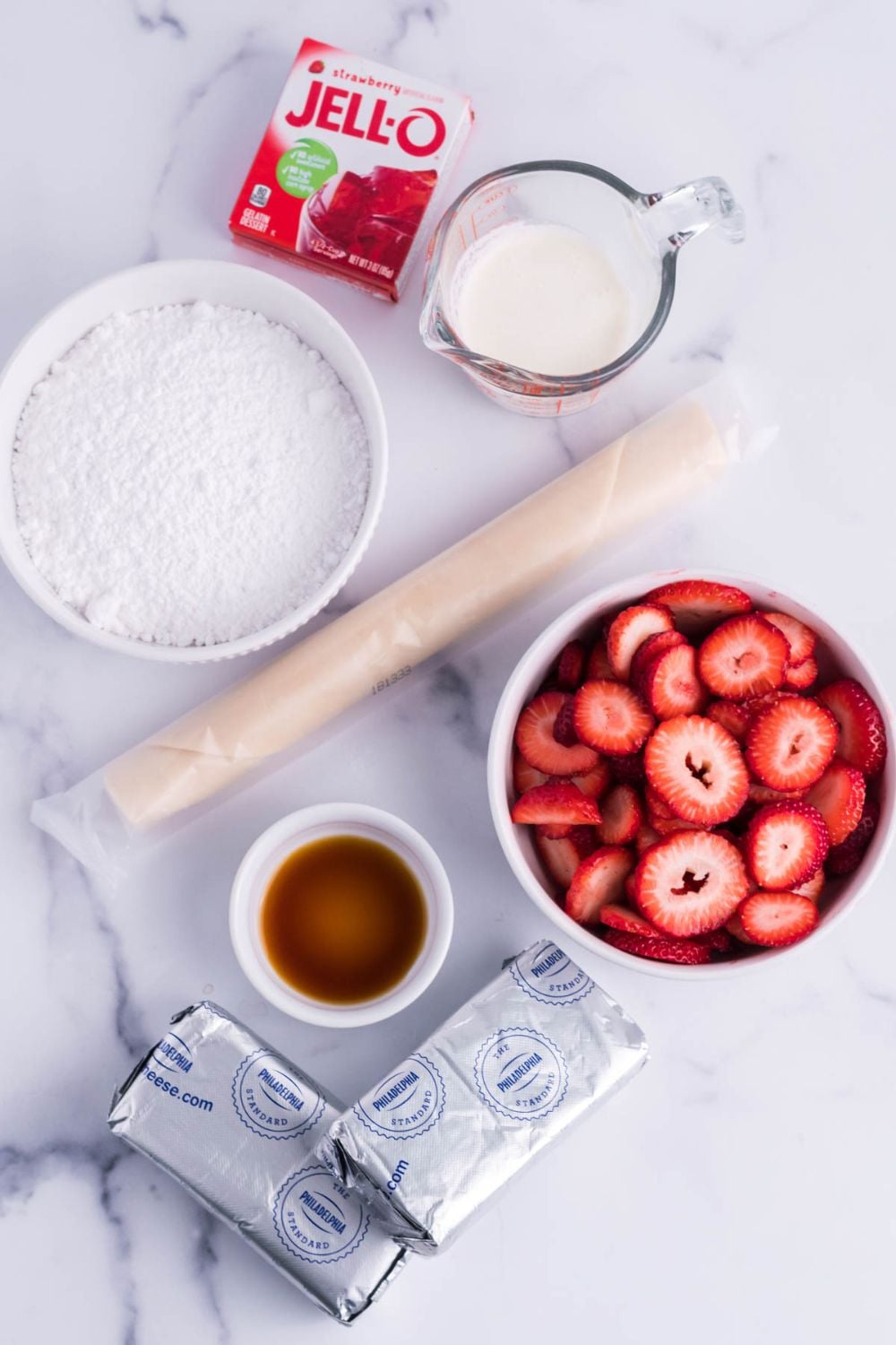 ingredients for a cream cheese and strawberry pie on a marble counter