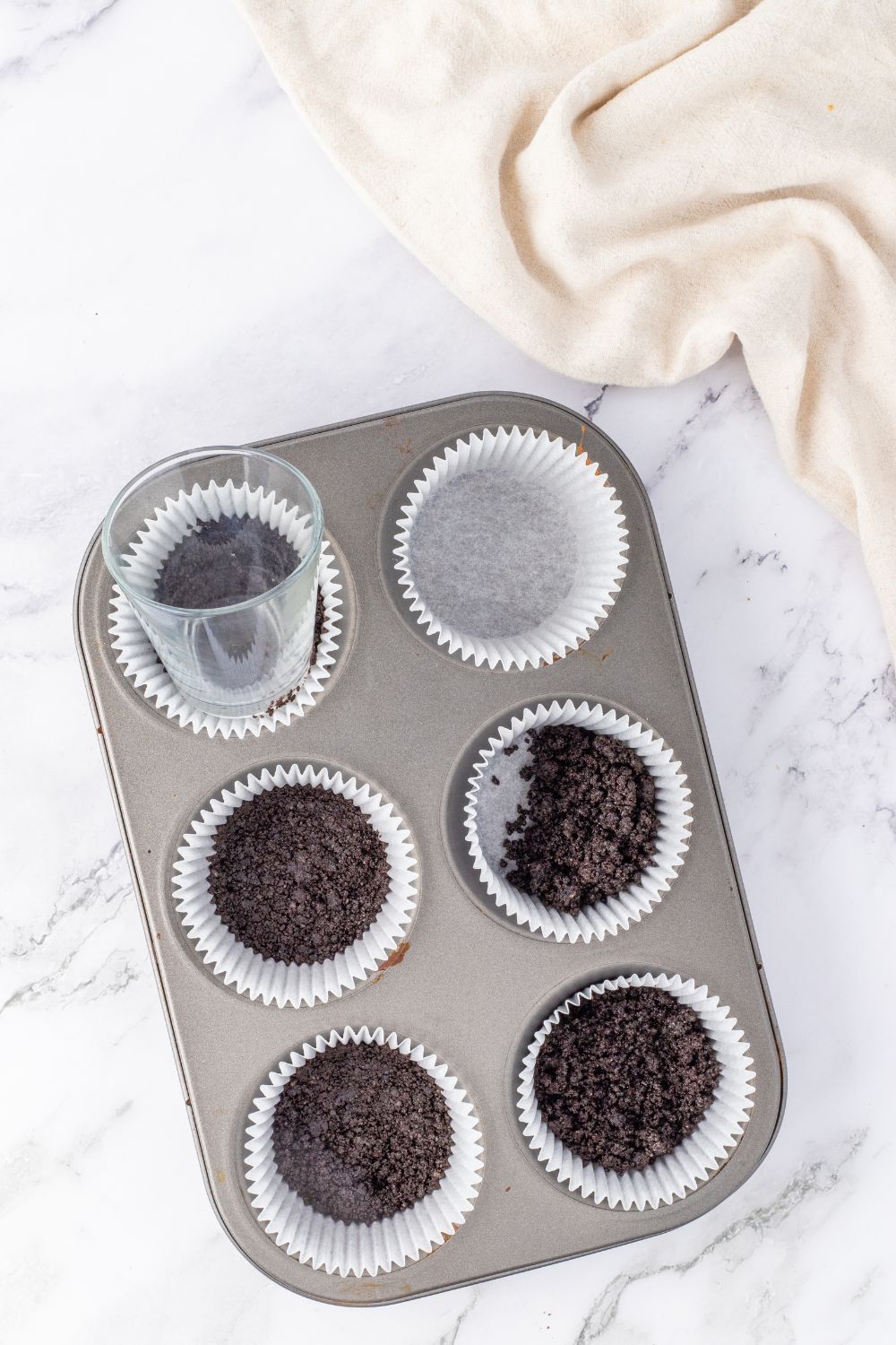 pressing Oreo cookie crust in muffin tin 