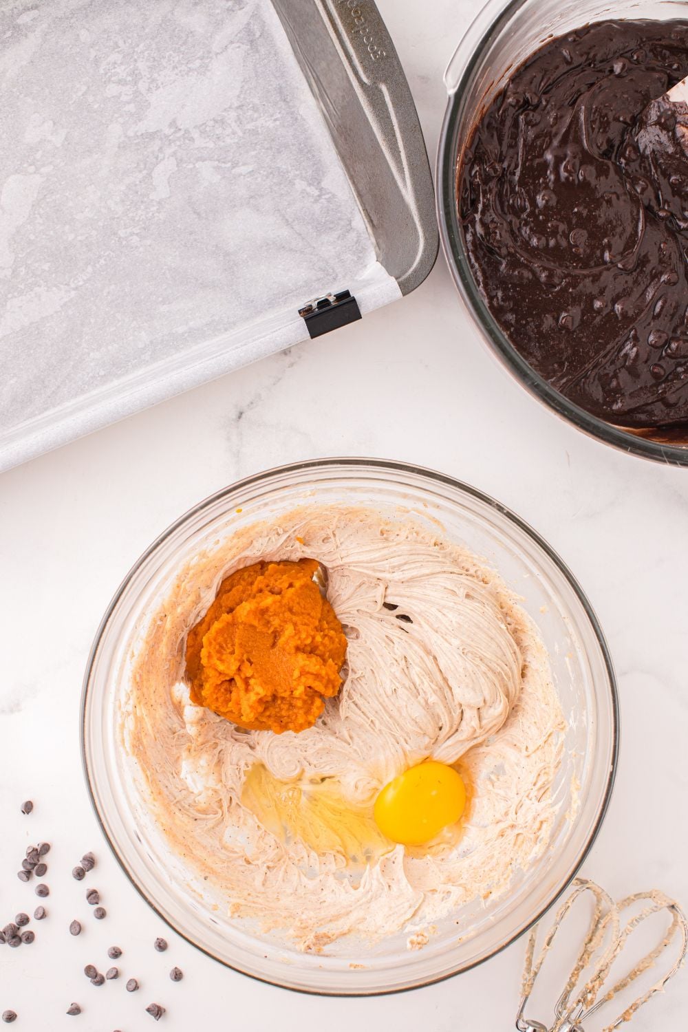 pumpkin cheesecake batter in a bowl with pan beside it on table