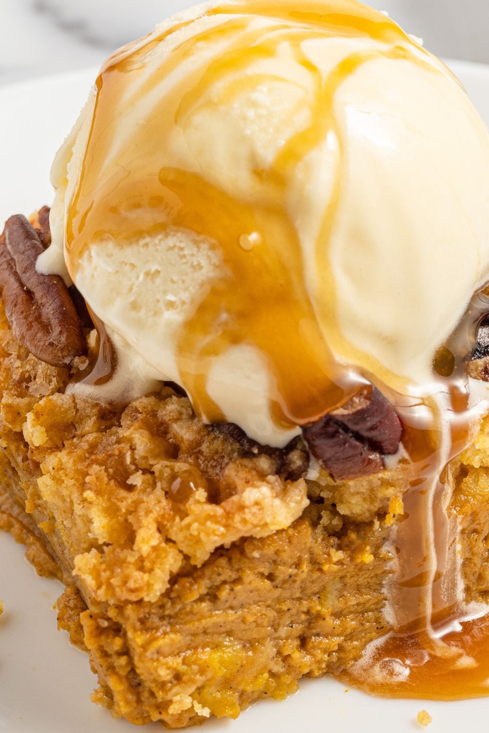 close up side view of pumpkin pie cake with ice cream on top
