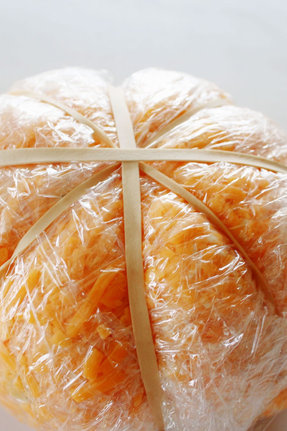 cheeseball wrapped in plastic and rubber bands around it