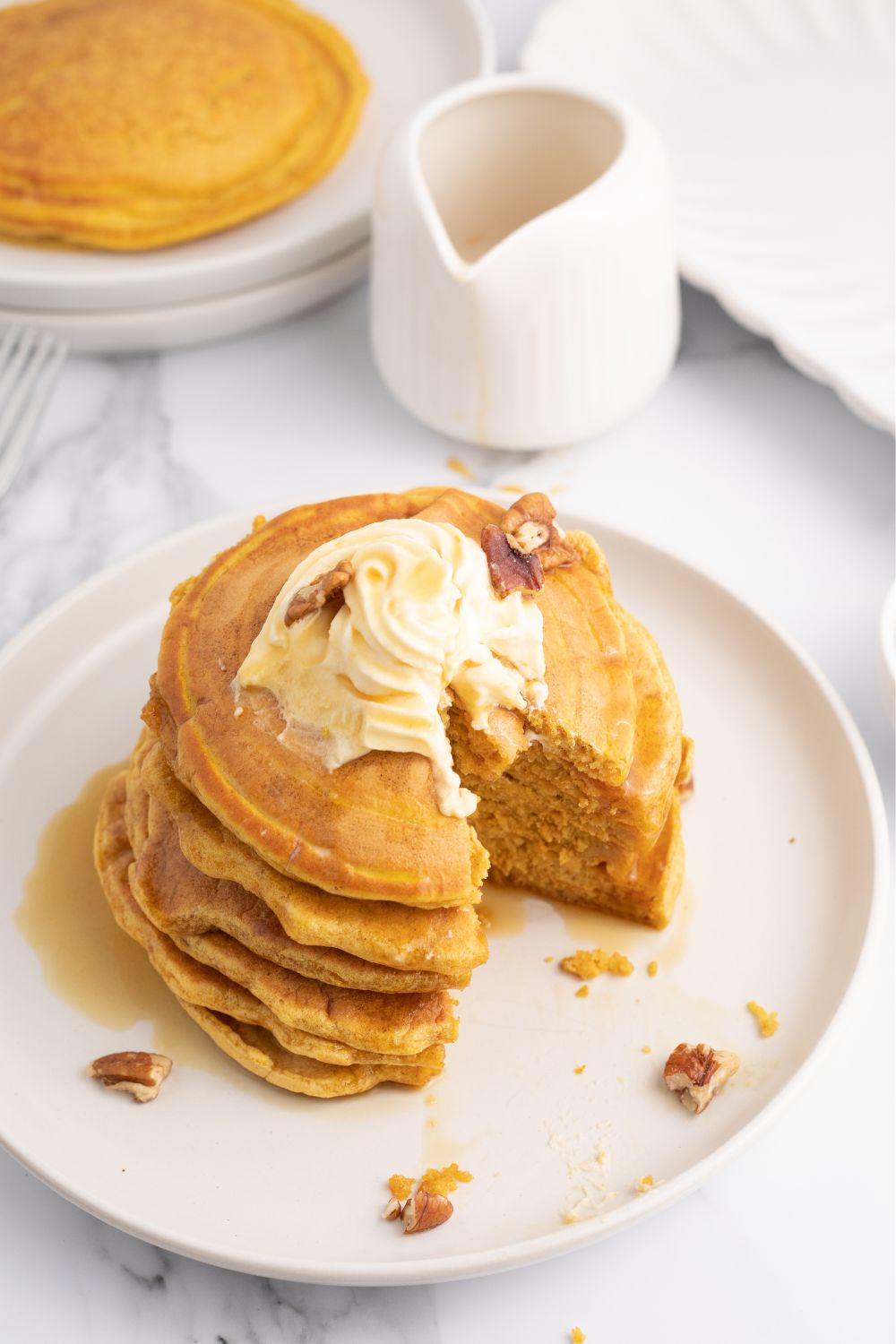 pumpkin spice pancakes stacked on a plate with half the pancakes cut up