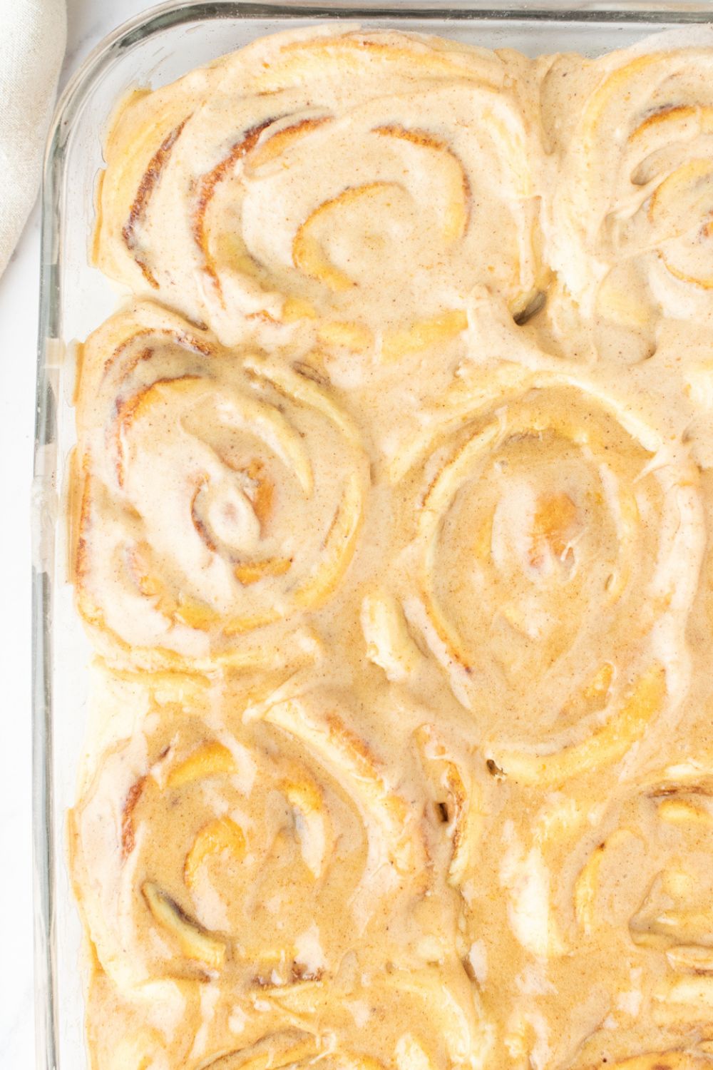 overhead shot of pumpkin cinnamon rolls in a glass pan on table