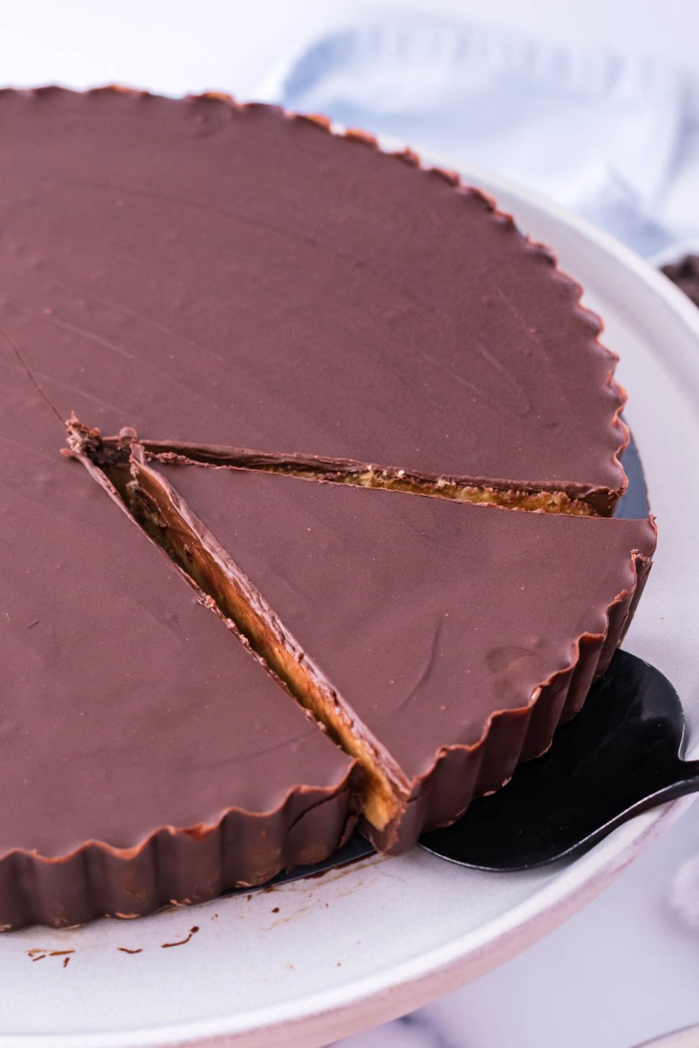 Giant Reese's Cup Pie with a slice cut and spatula under it 
