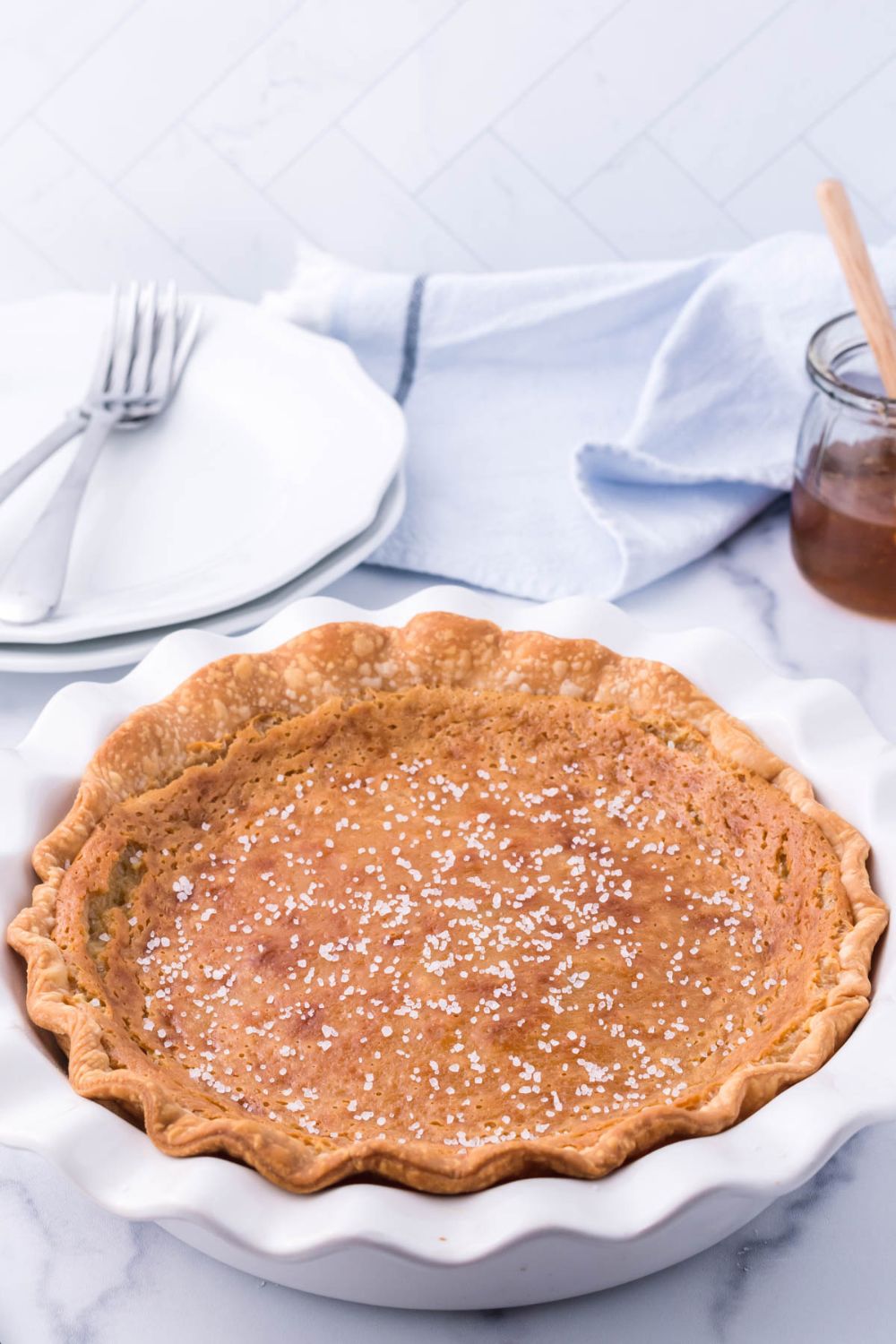 honey pie in a pie pan on table with plates and forks behind it