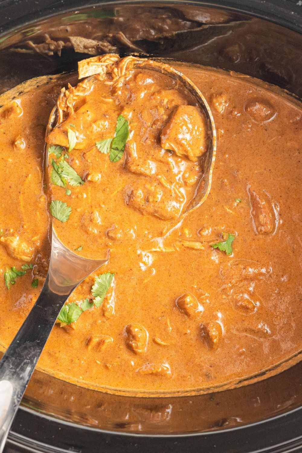 slow cooker chicken tikka masala with ladle inside the crockpot
