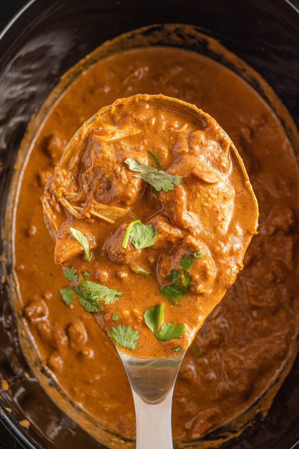 spatula full of masala chicken with herbs on top