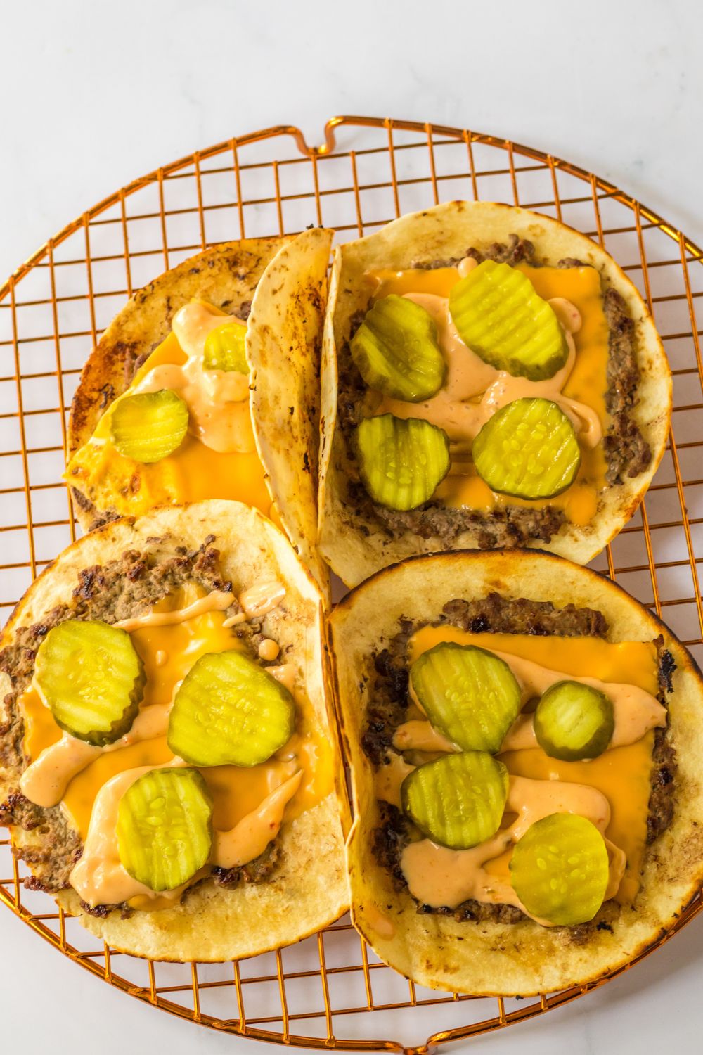 smash tacos topped with cheese and pickles