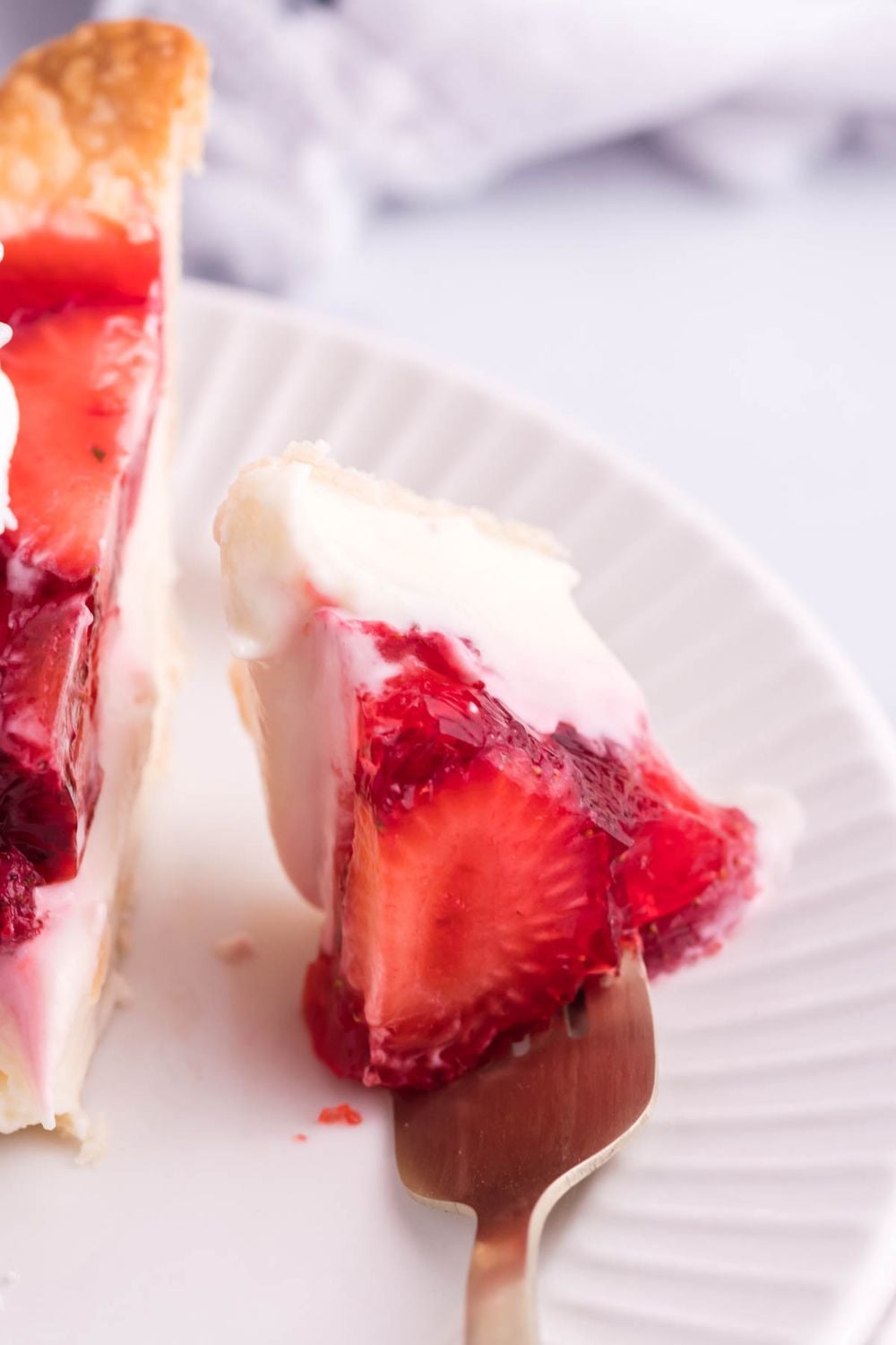 strawberry cheese pie with a fork full of a bite