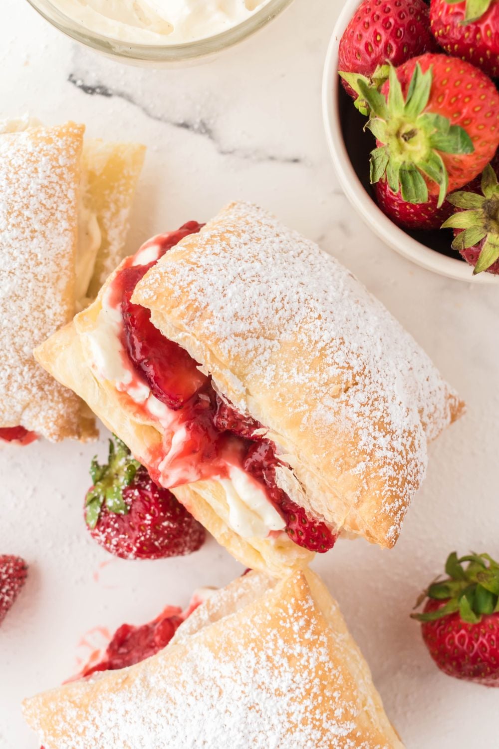 strawberry puffs on plate with a bowl of strawberries on the side on a marble counter
