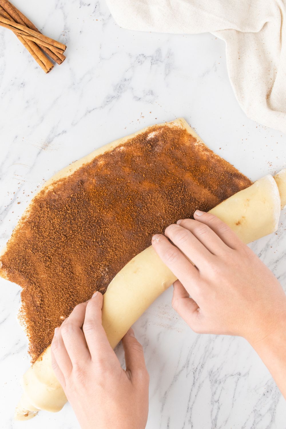 rolling cinnamon roll dough into a rolled tube