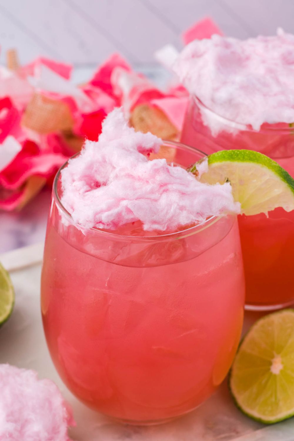 cotton candy on top of cocktail with lime wedge on side
