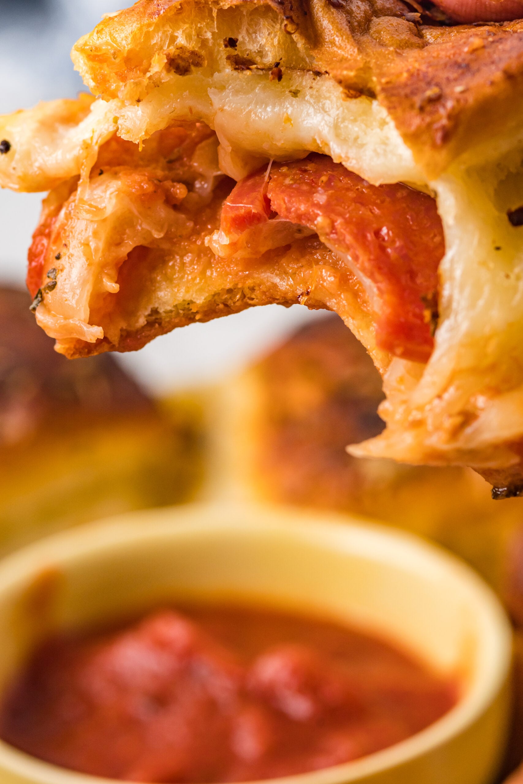 pepperoni Pizza slider with a bite missing showing the inside and gooey cheese