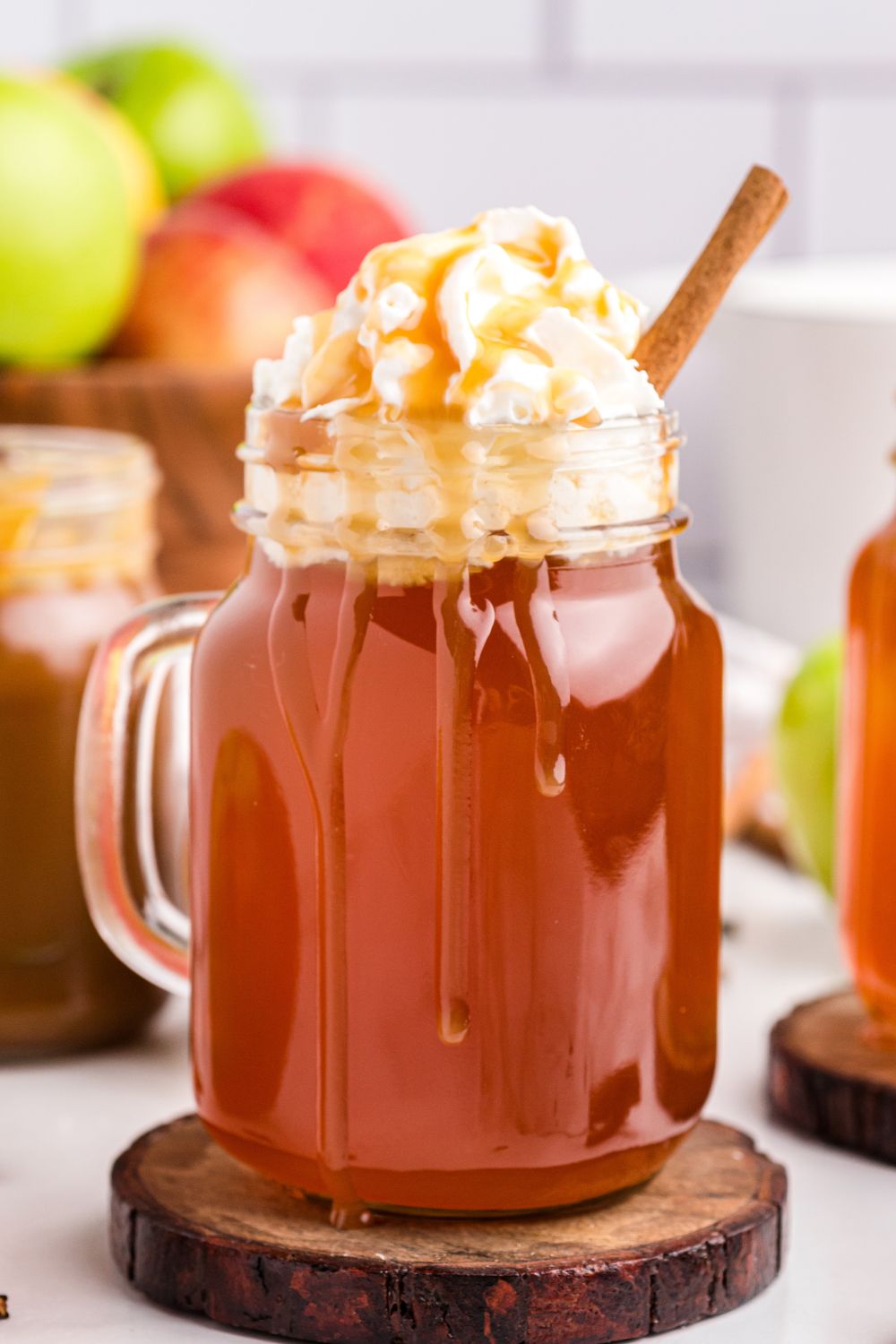 apple cider with caramel and whipped cream on top in a mason jar mug