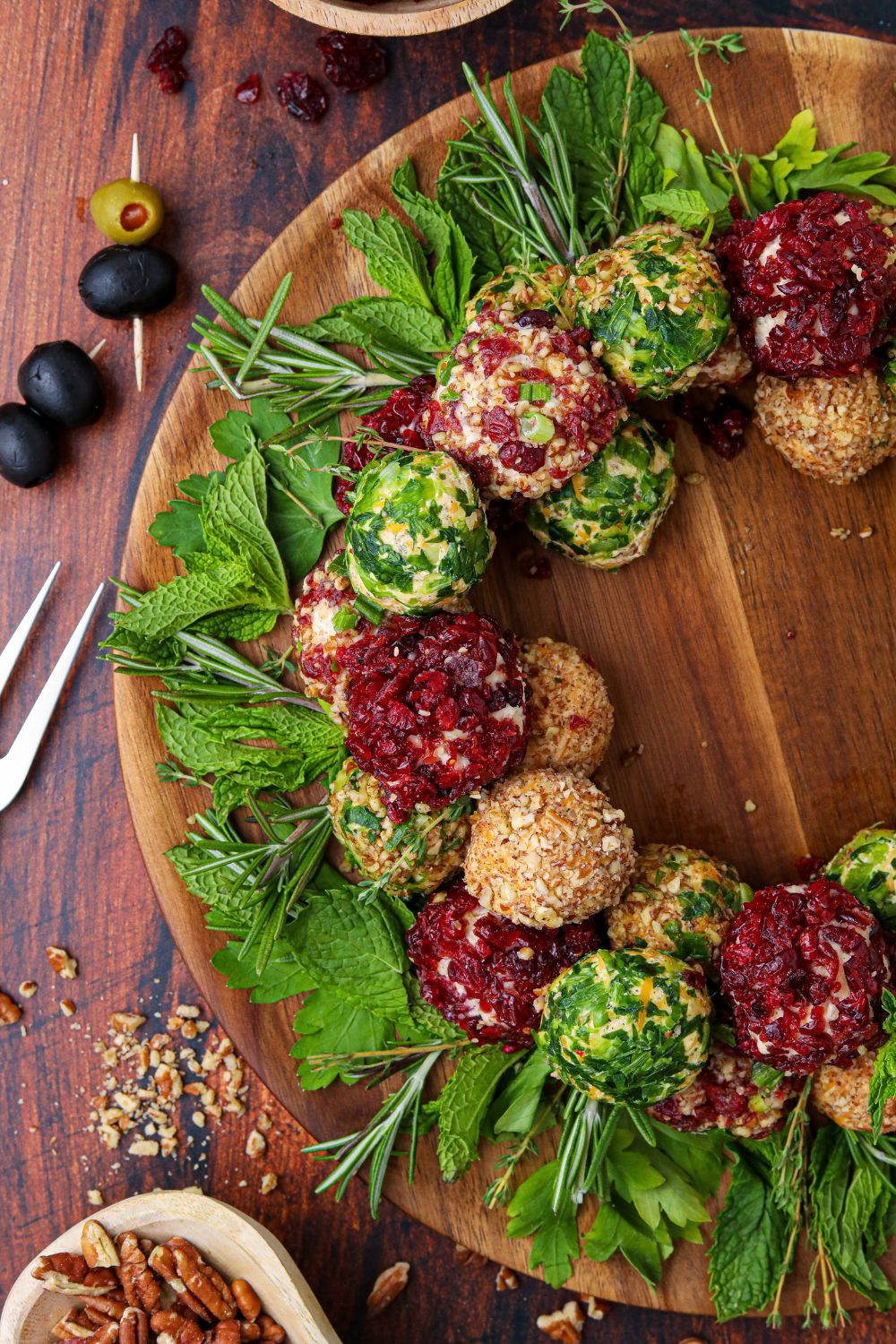 half of a cheese ball wreath in image with food around a wooden table